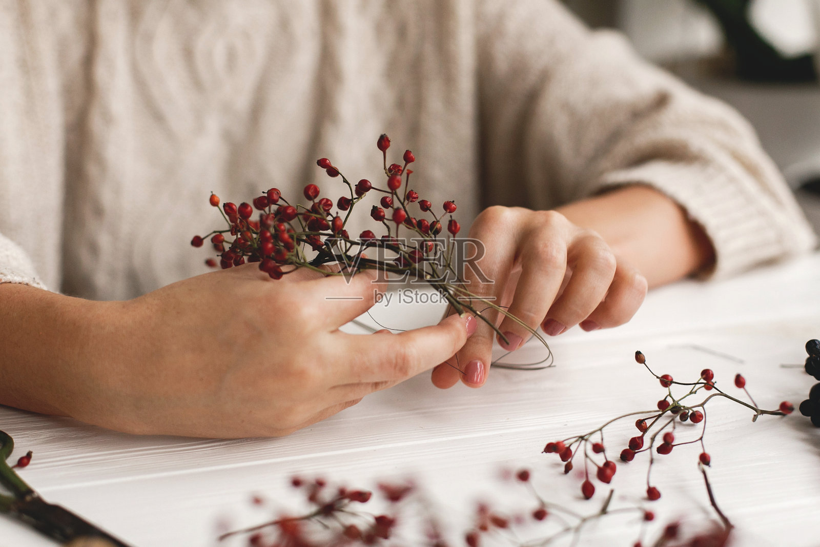花商制作简单的圣诞花环与红色浆果在白色的木制桌子上照片摄影图片