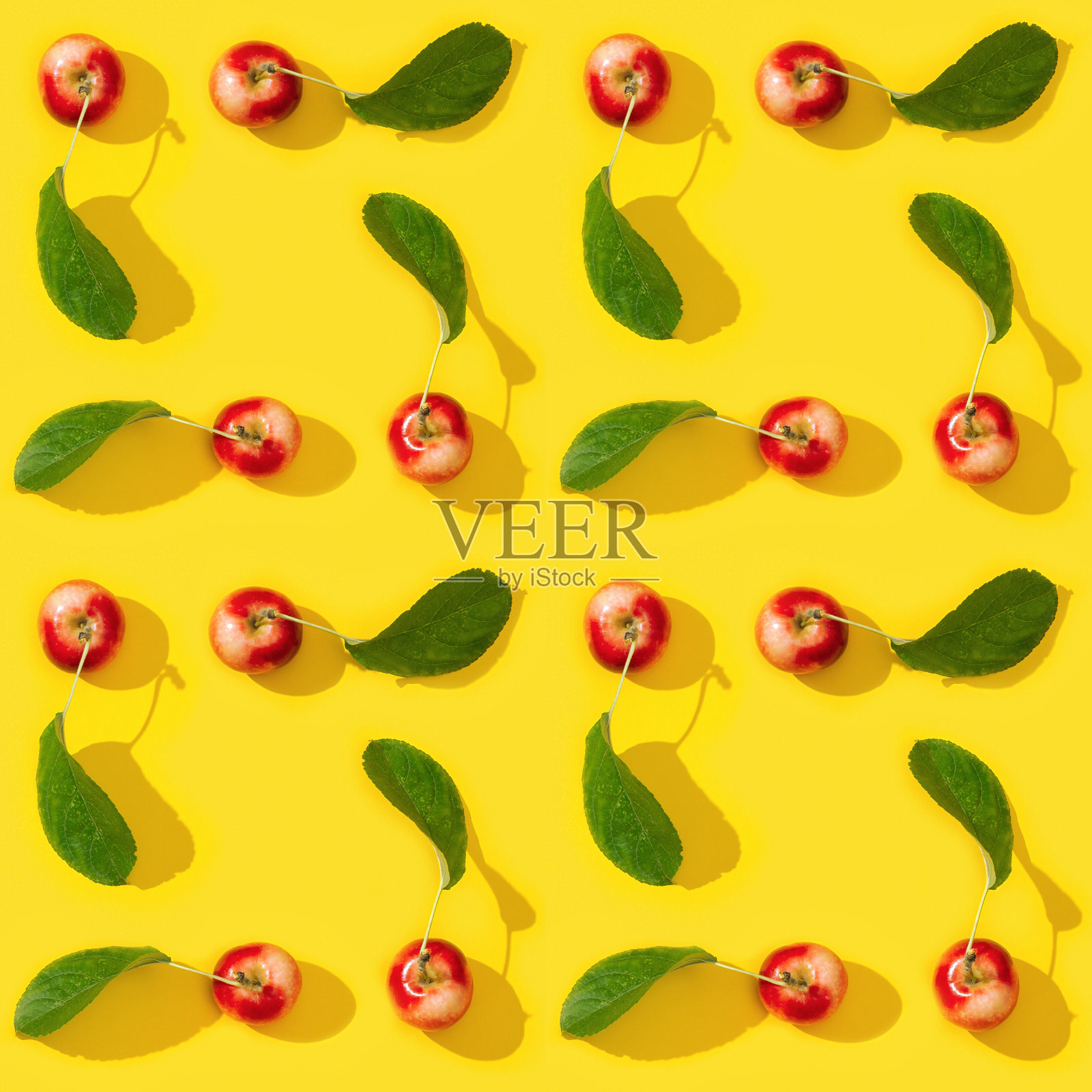从成熟的小红苹果和绿色的叶子在黄色背景无缝规则的创意图案。照片摄影图片
