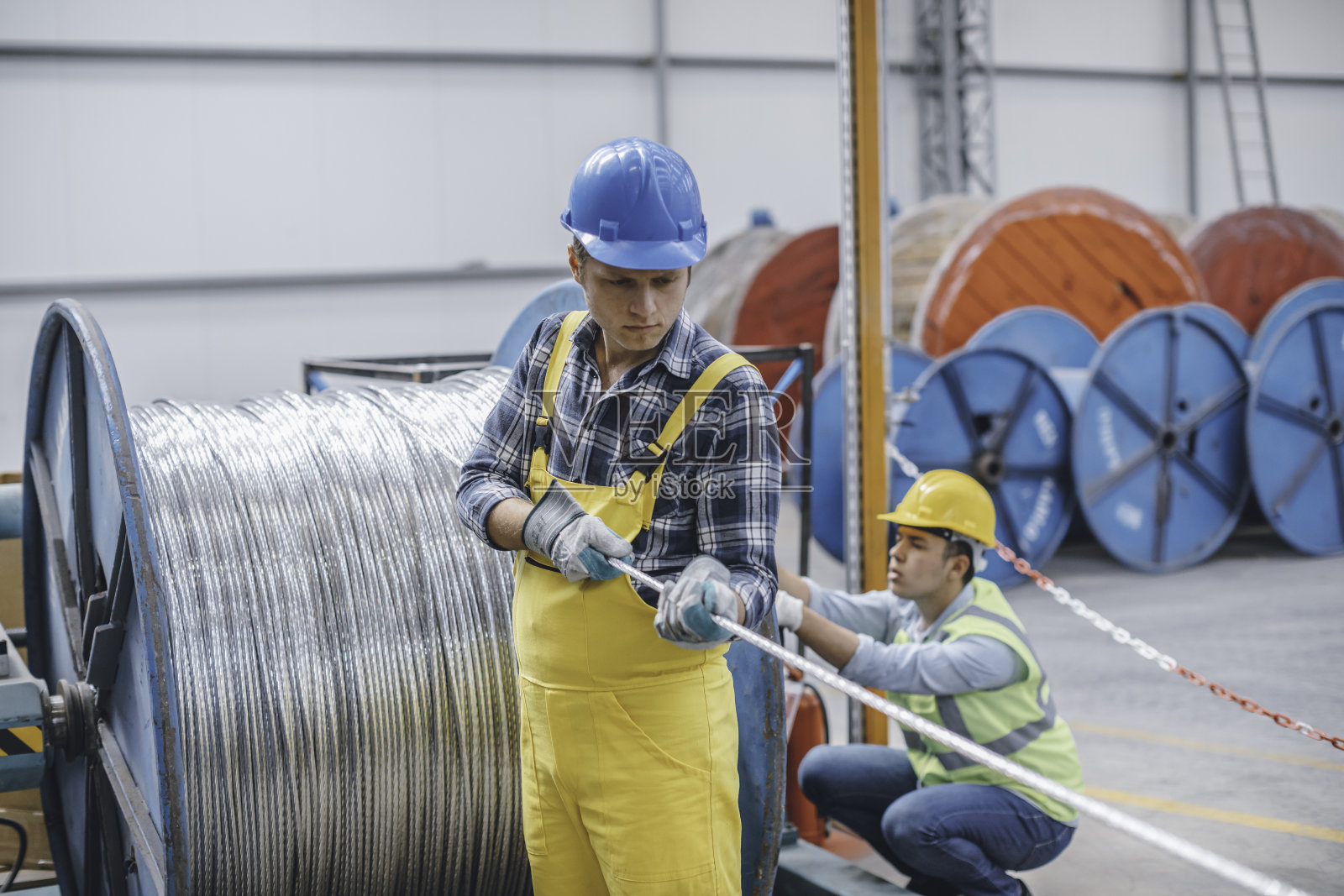 年轻商人的肖像与电缆辊在工厂工作照片摄影图片
