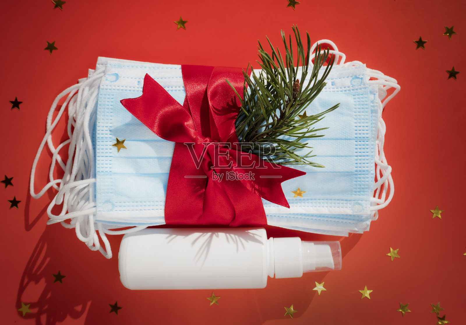 卫生口罩抗菌凝胶作为礼物，用红色丝带装饰2021年圣诞节和新年的背景。假日自我隔离和冠状病毒大流行概念照片摄影图片