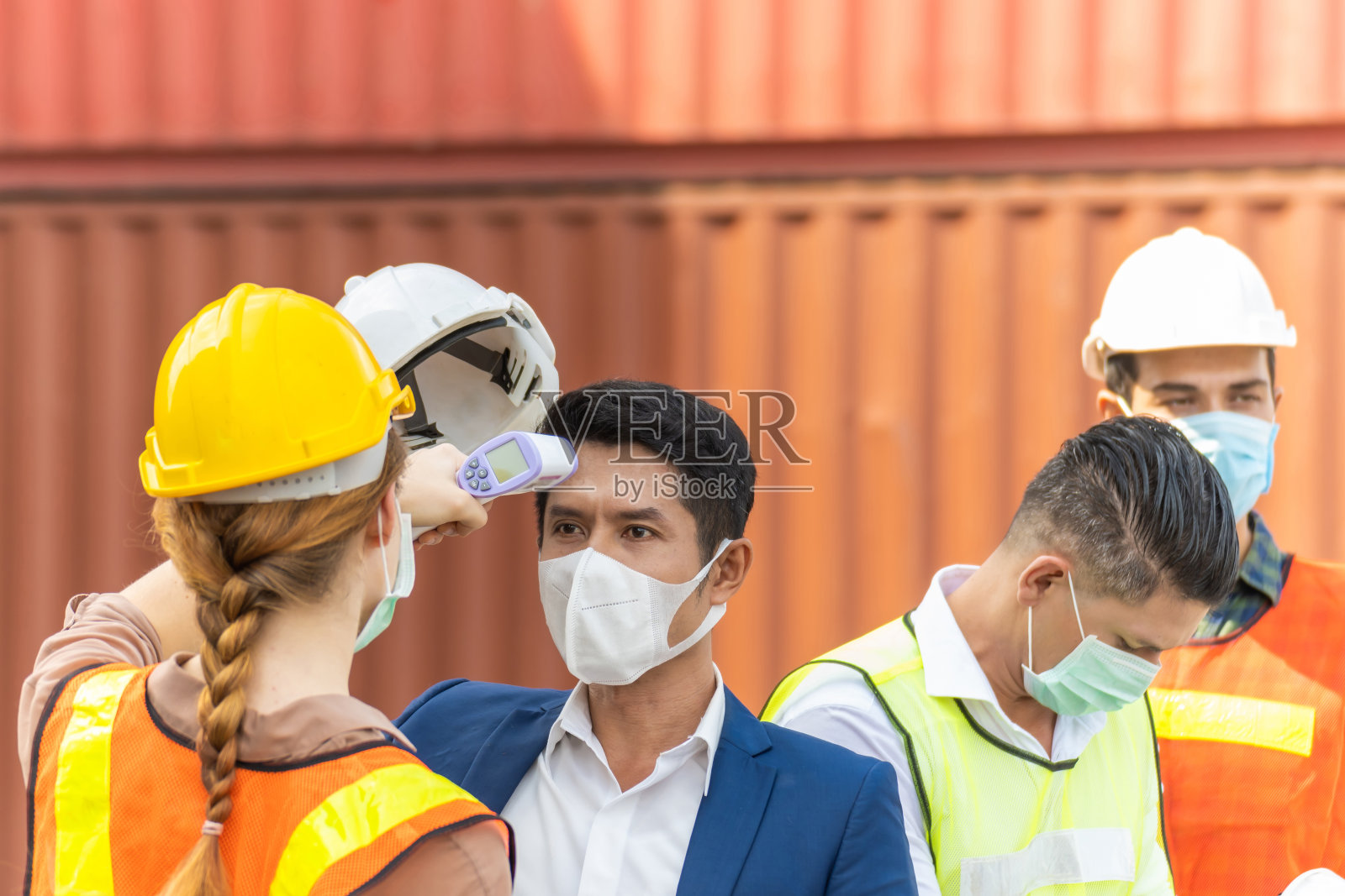 工业工人妇女温度检查发烧数字温度计与工程师男子与货物集装箱在背景集装箱货港，工业，物流进出口概念照片摄影图片