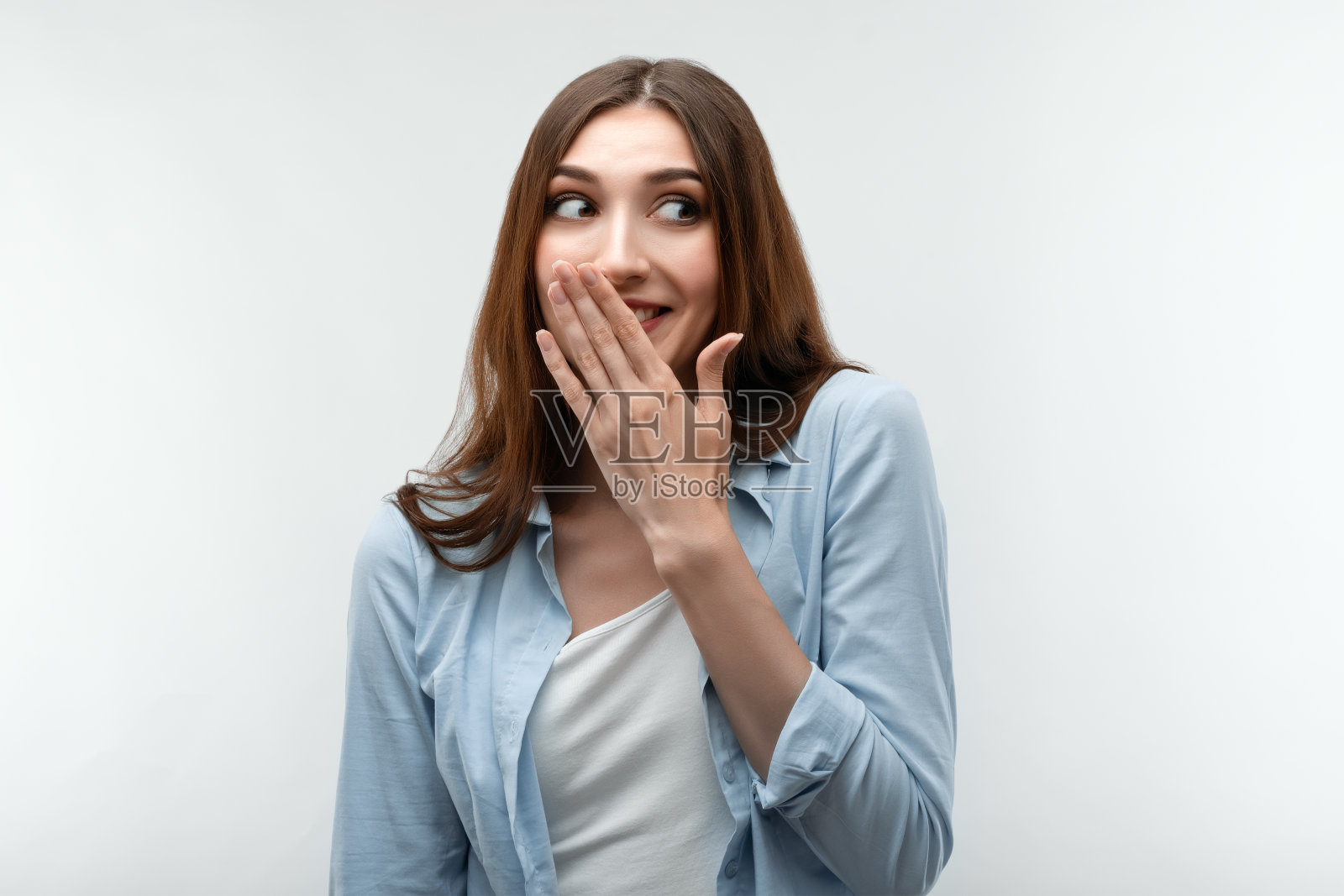 有魅力的女孩在休闲衣服用手捂住她的嘴。人的情绪、表情概念照片摄影图片