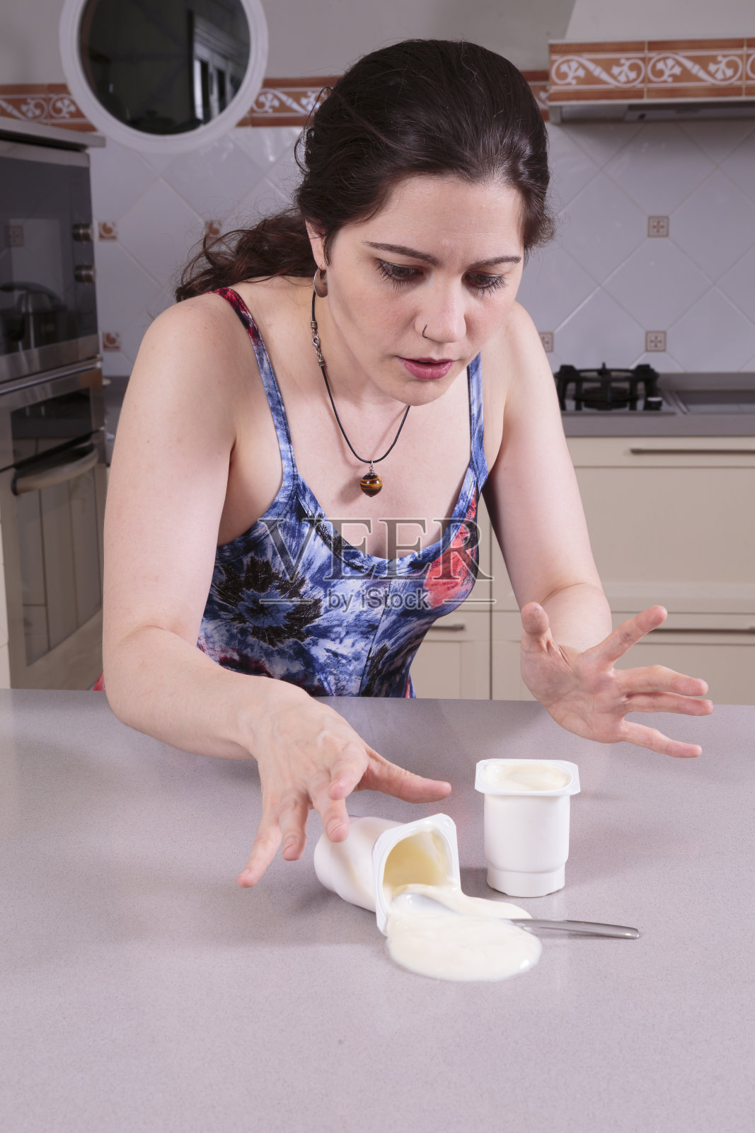一个年轻漂亮的女人在清洗酸奶时不小心洒了照片摄影图片