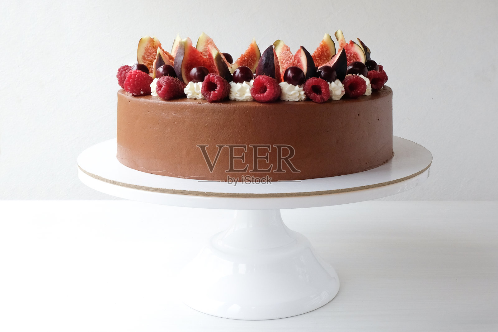 以新鲜的覆盆子、樱桃、无花果装饰的蛋糕。照片摄影图片