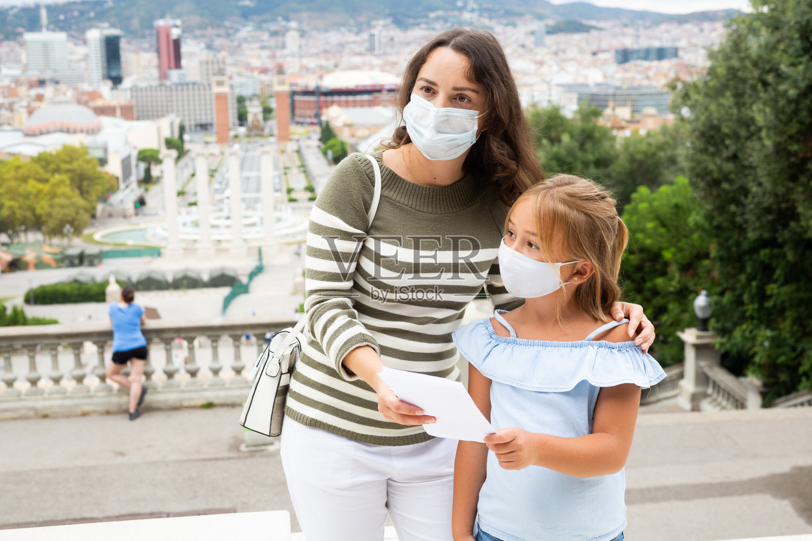 在欧洲城市的观景台上，母亲和女儿戴着防护面具的肖像照片摄影图片