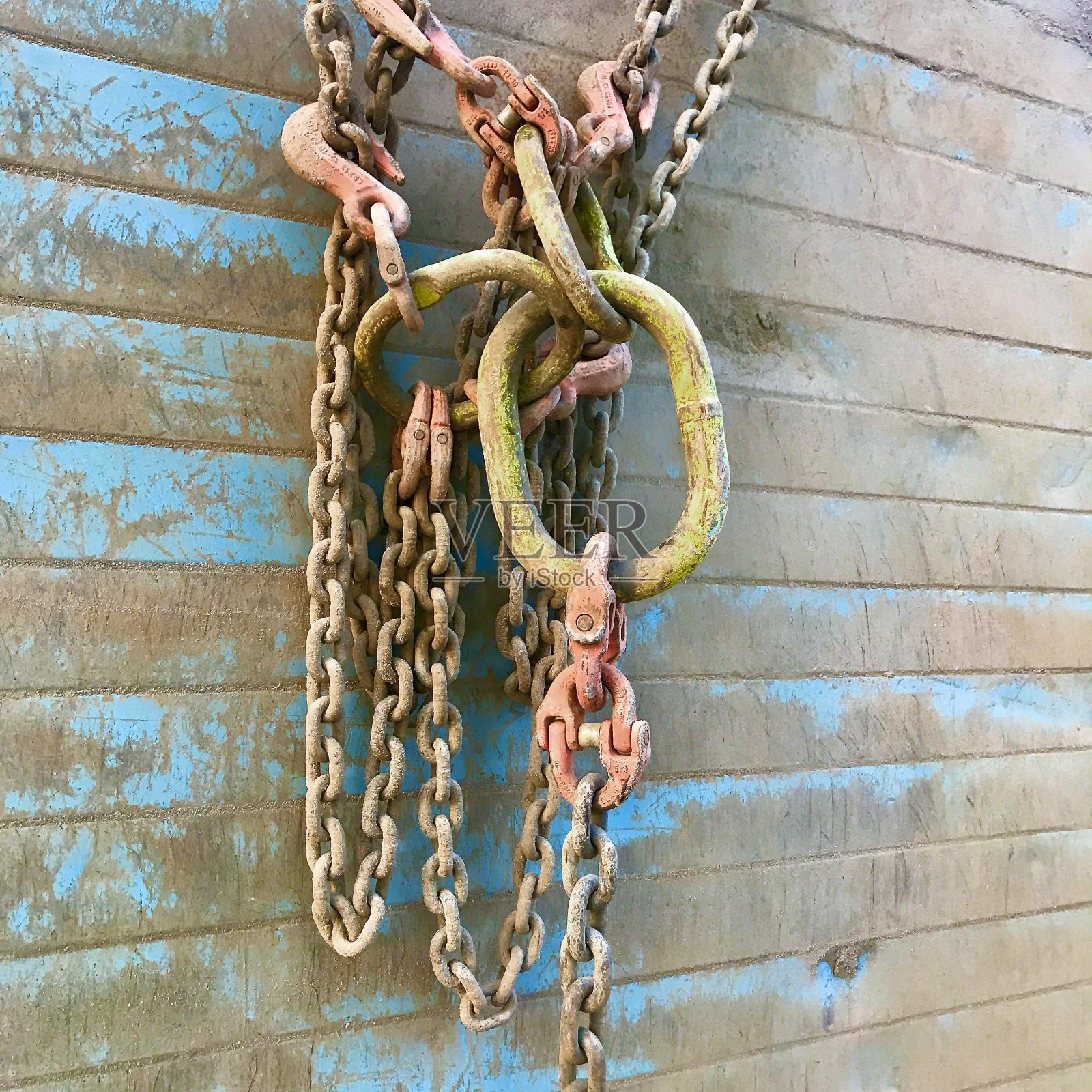 挂在金属墙上的带有挂钩和连接件的链条照片摄影图片