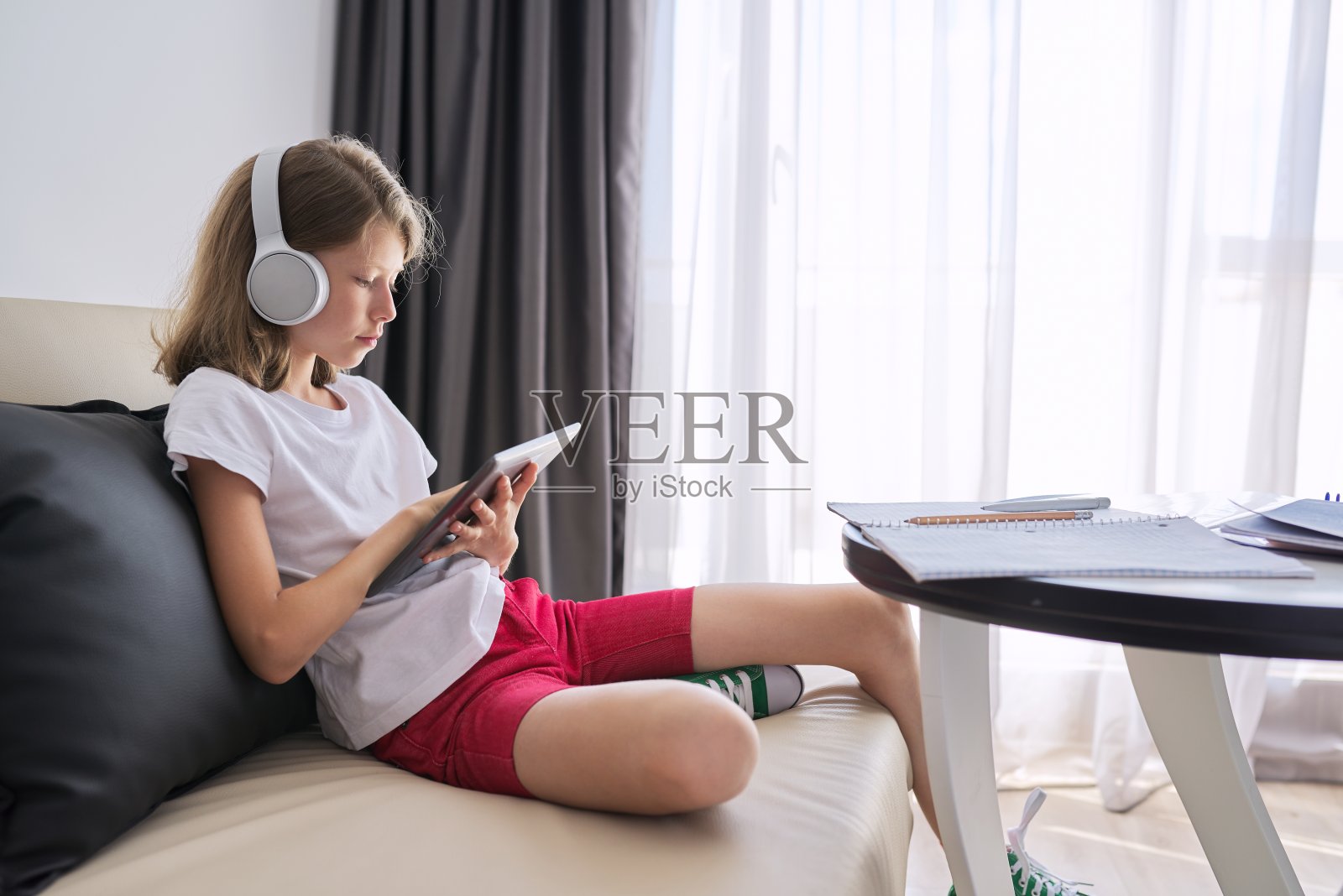 女孩在家上网学习，孩子戴着耳机用着平板电脑照片摄影图片