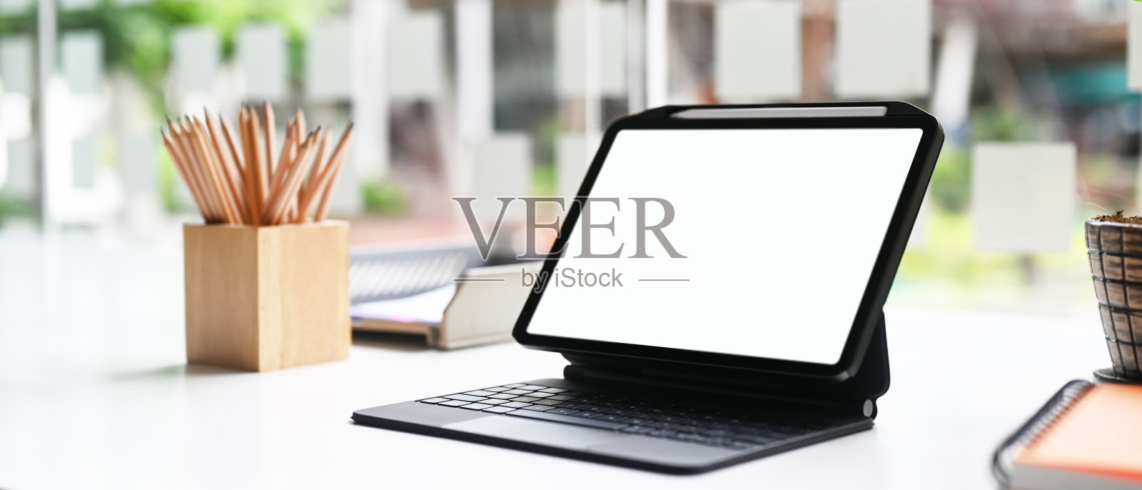 数码平板电脑和键盘壳与空白屏幕上的创意工作空间。照片摄影图片