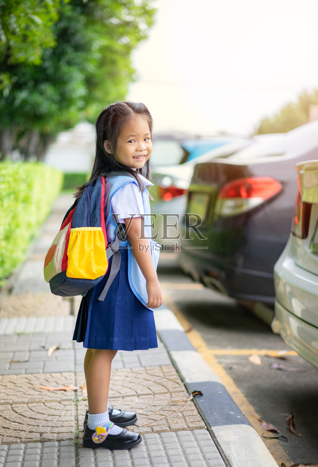 快乐的小女孩穿着泰国校服站在公园里，准备回学校照片摄影图片