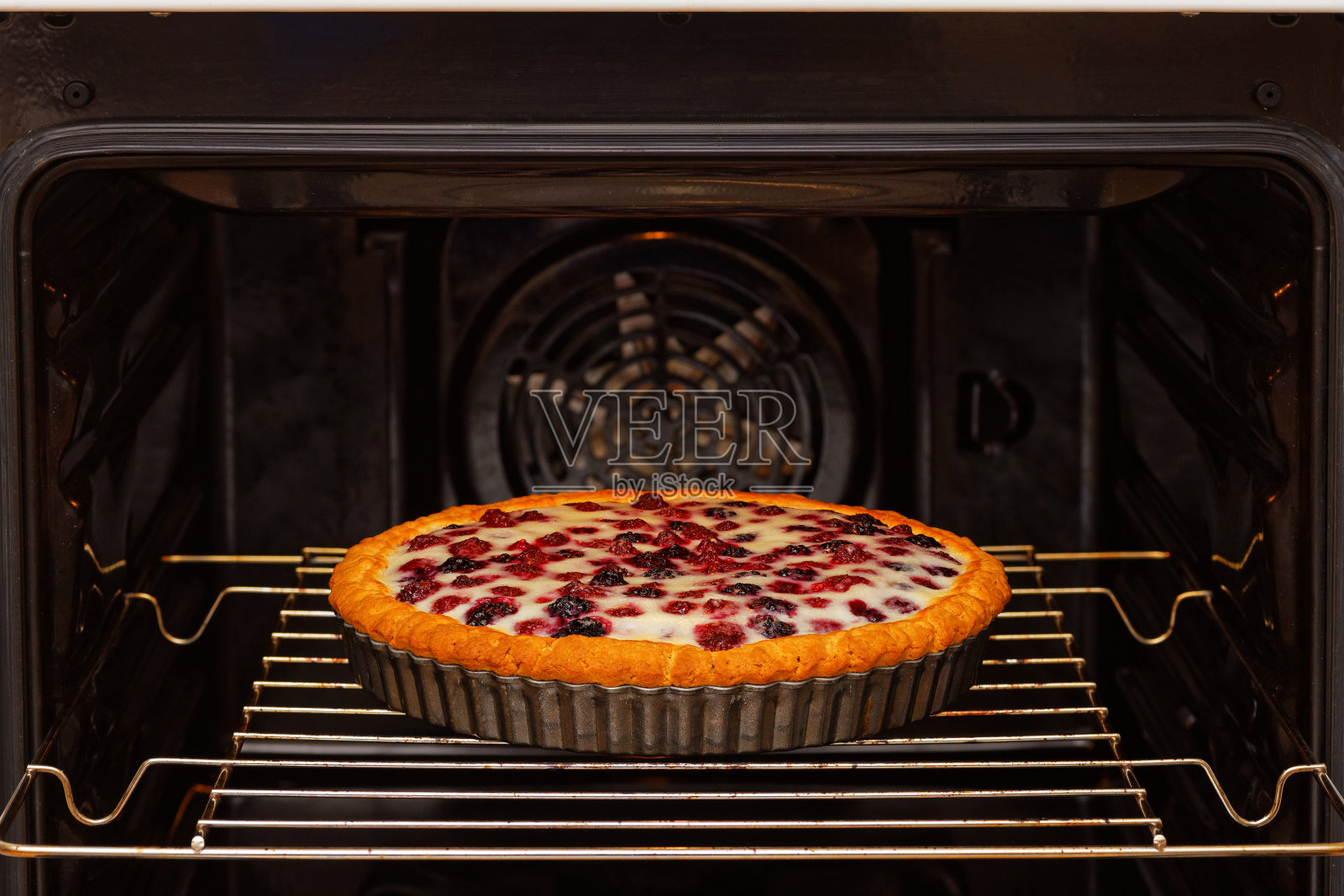 特写自制浆果派在家庭烤箱烤。浅的焦点。照片摄影图片