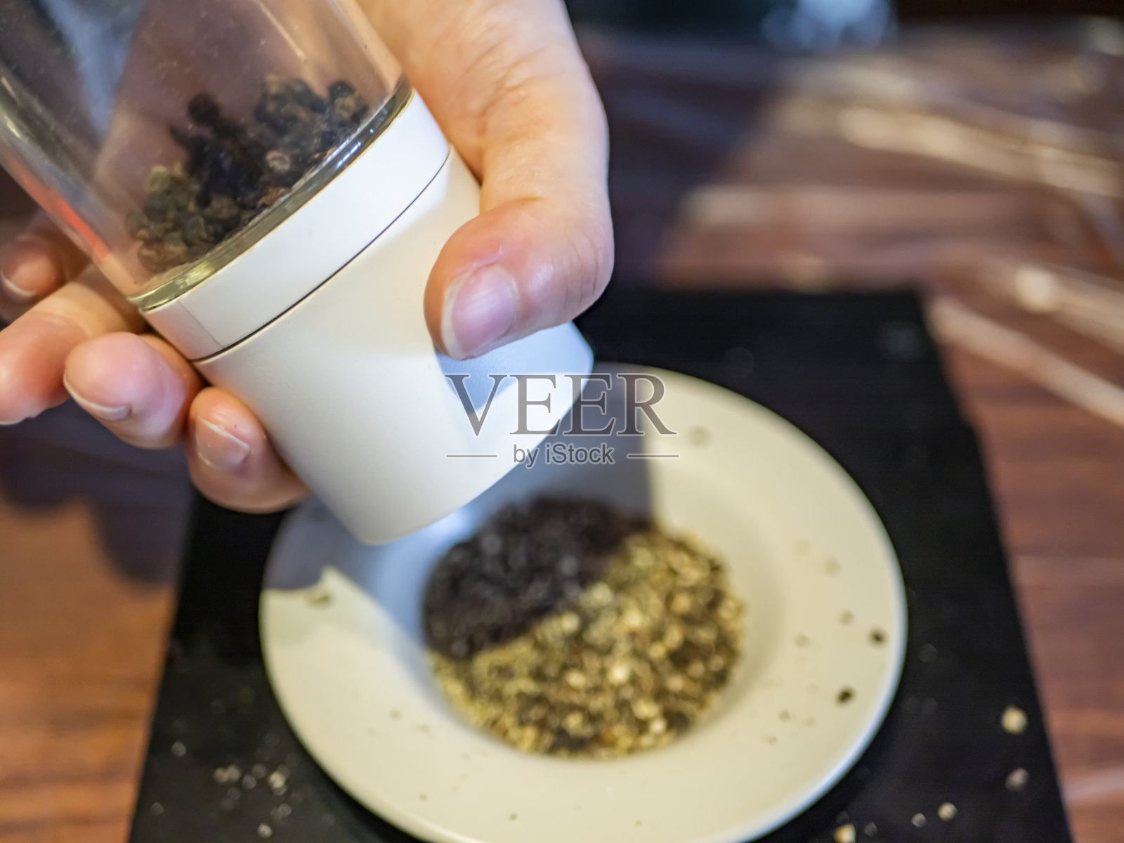 一个年轻的女人把黑胡椒磨成粉照片摄影图片