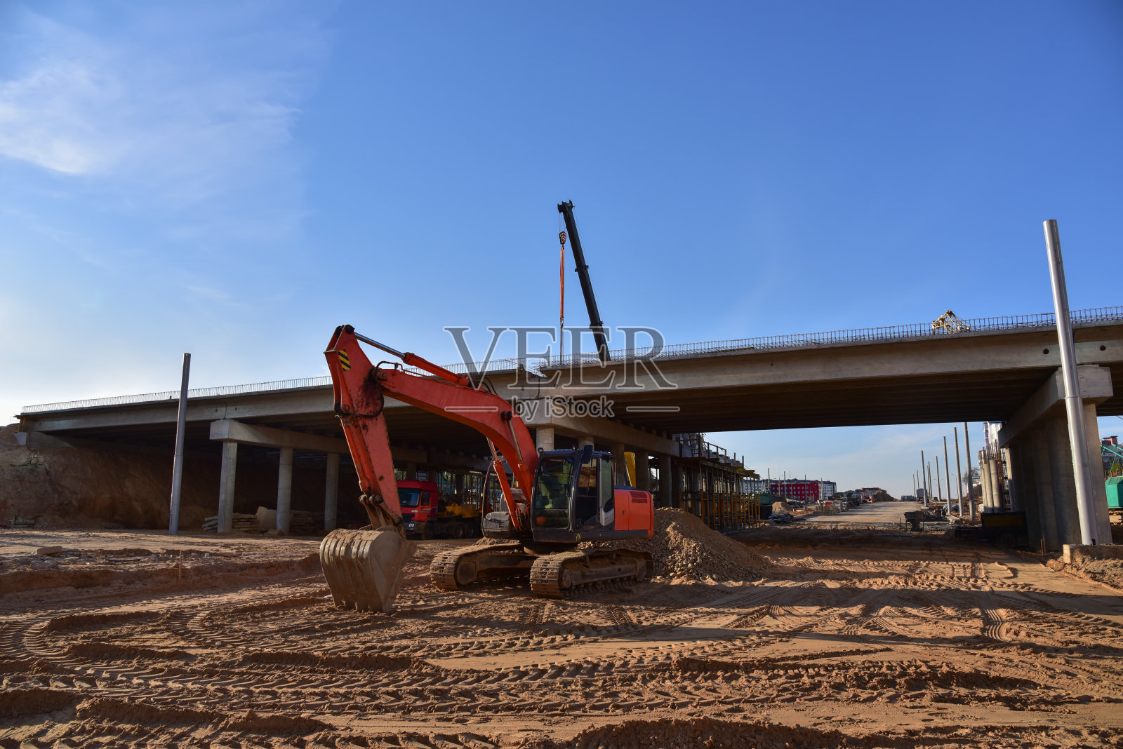 挖掘机在公路坡道和桥梁工程中工作。环岛和交通桥梁建设。在交通高速公路、道路交叉路口和高速公路上进行道路施工。桥项目工作照片摄影图片