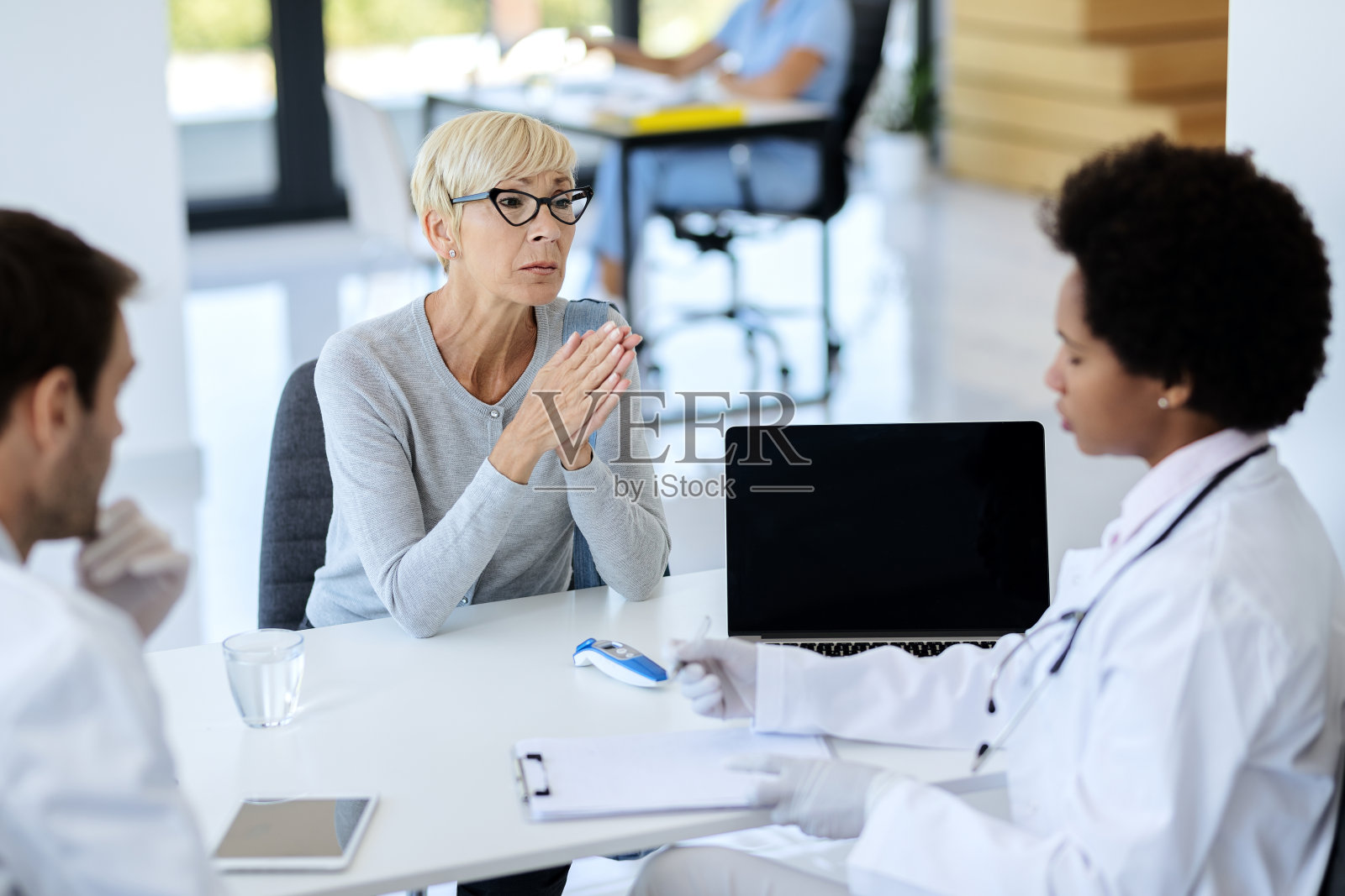 心烦意乱的成熟女人有医疗预约与她的医生在诊所。照片摄影图片