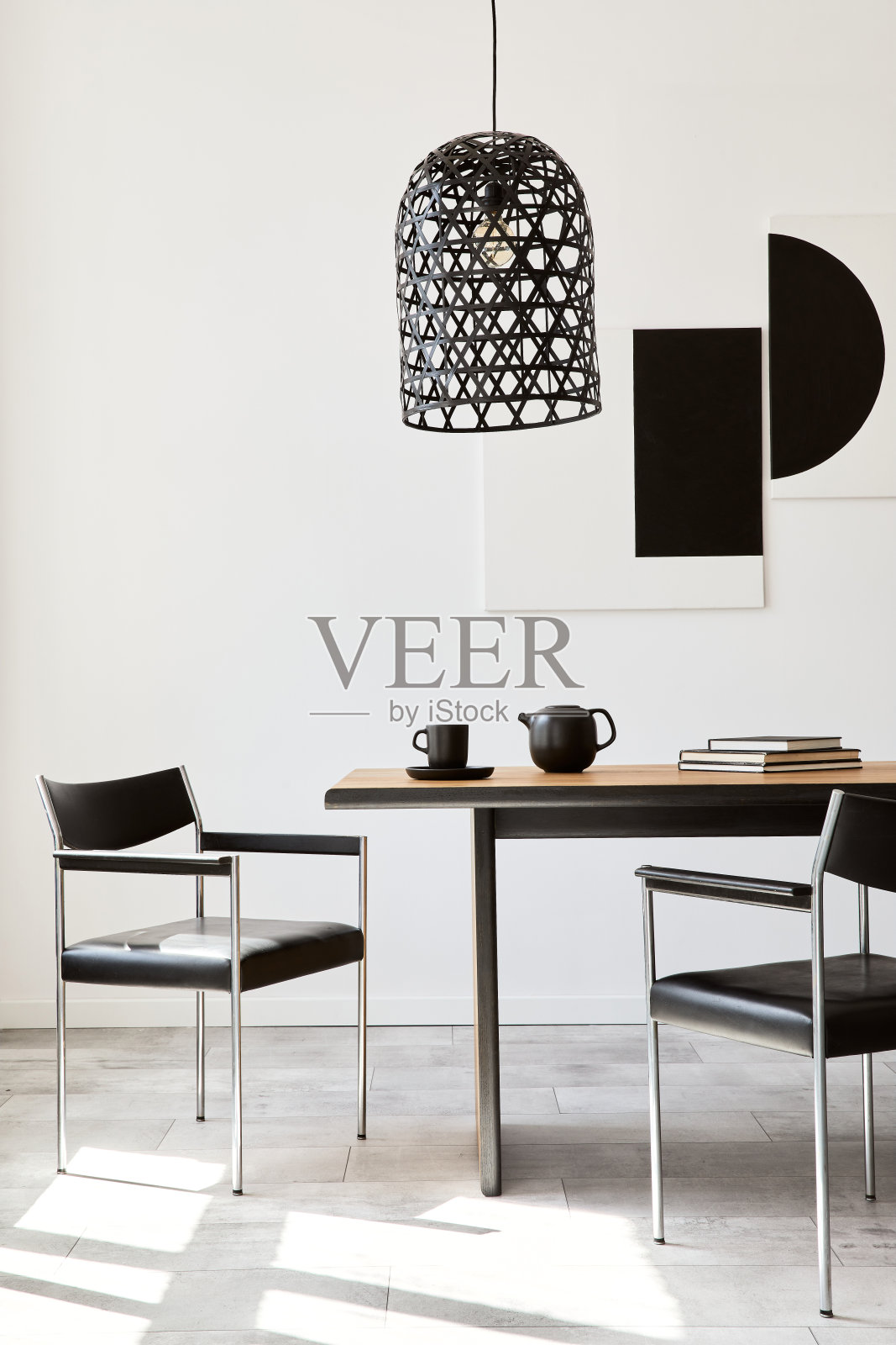 时尚的餐厅内部设计木制家庭餐桌，黑色椅子，茶壶与马克杯，模拟艺术画在墙上和现代家居装饰优雅的配件。模板。照片摄影图片