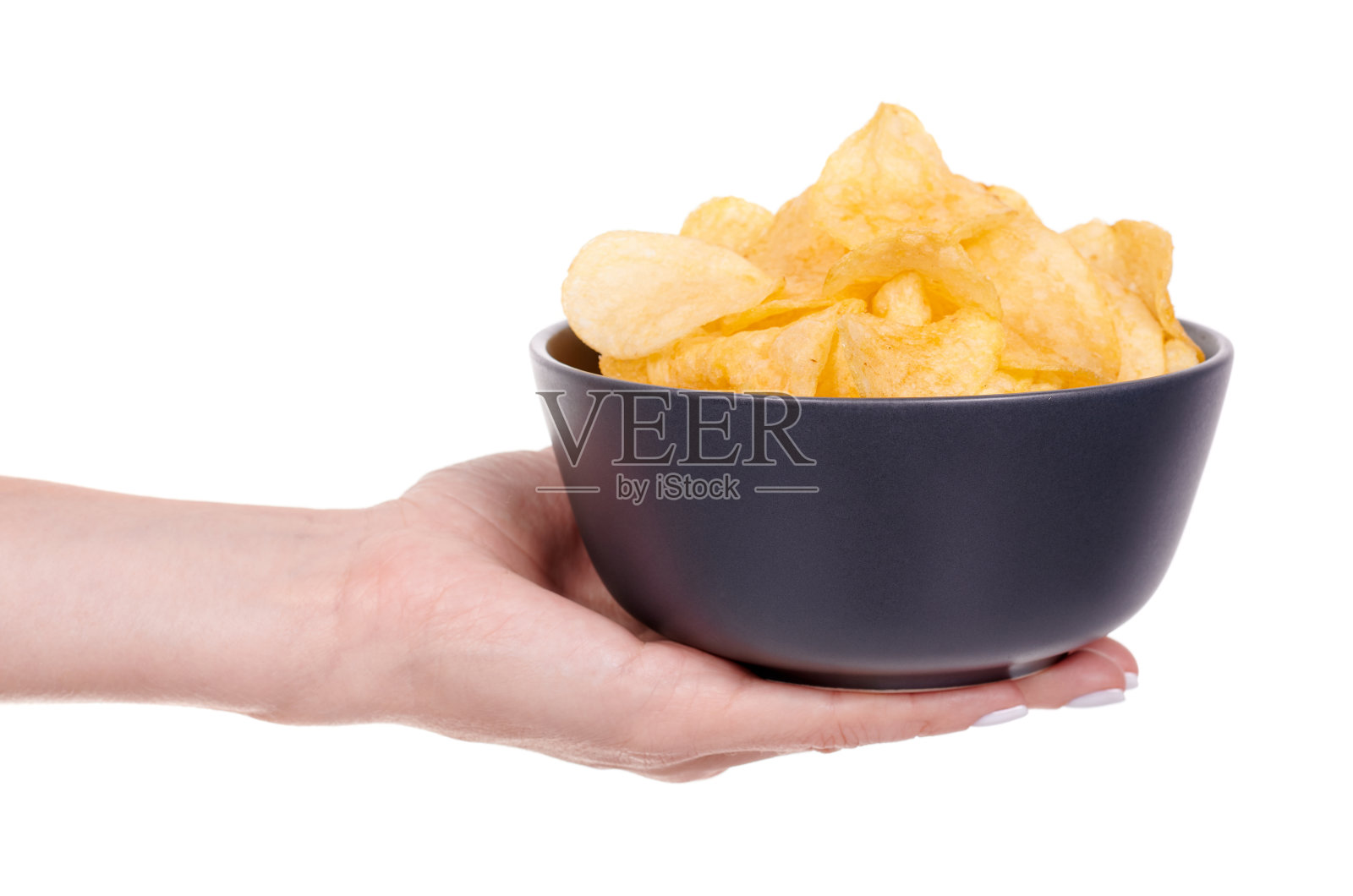 用手把金色的薯片放在黑色的碗里，孤立在白色的背景上。照片摄影图片