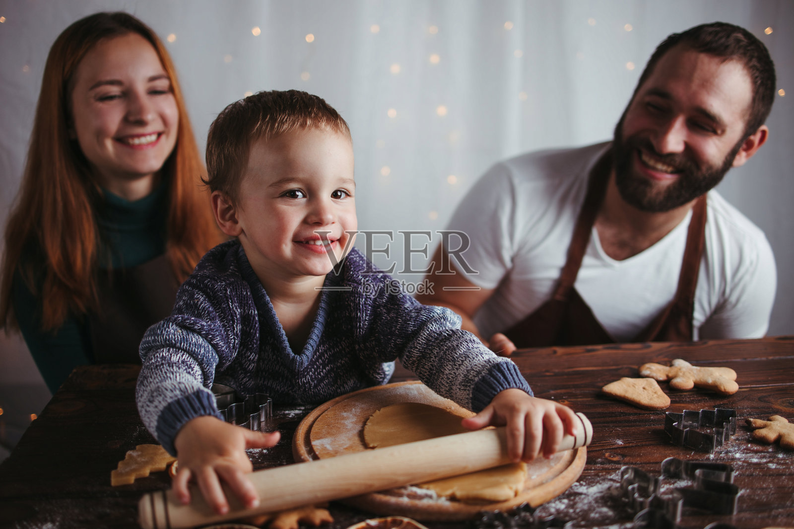 妈妈，爸爸和儿子在揉姜饼面团照片摄影图片