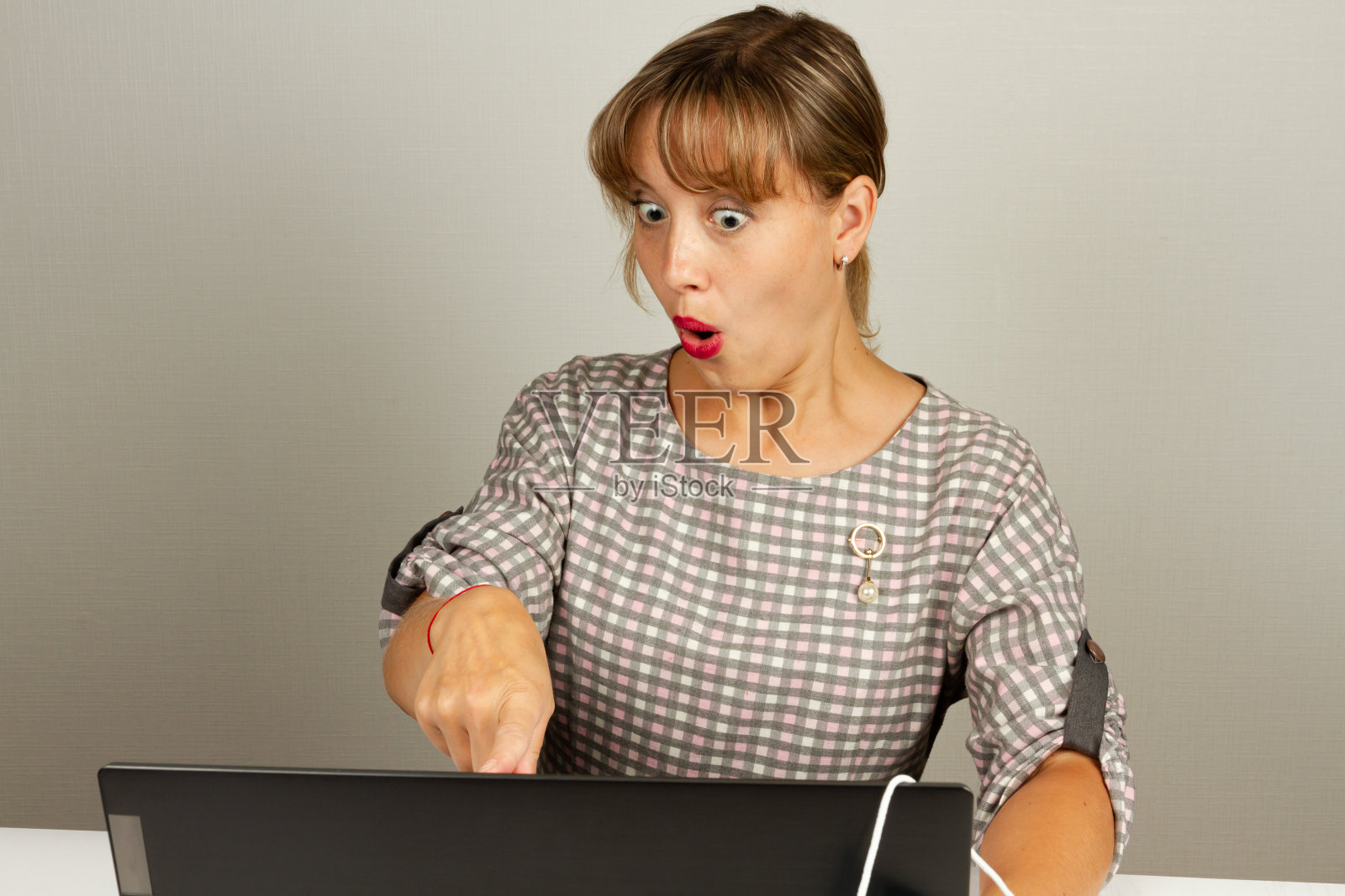 美丽的女孩对在办公室里摆弄电脑感到很惊讶照片摄影图片