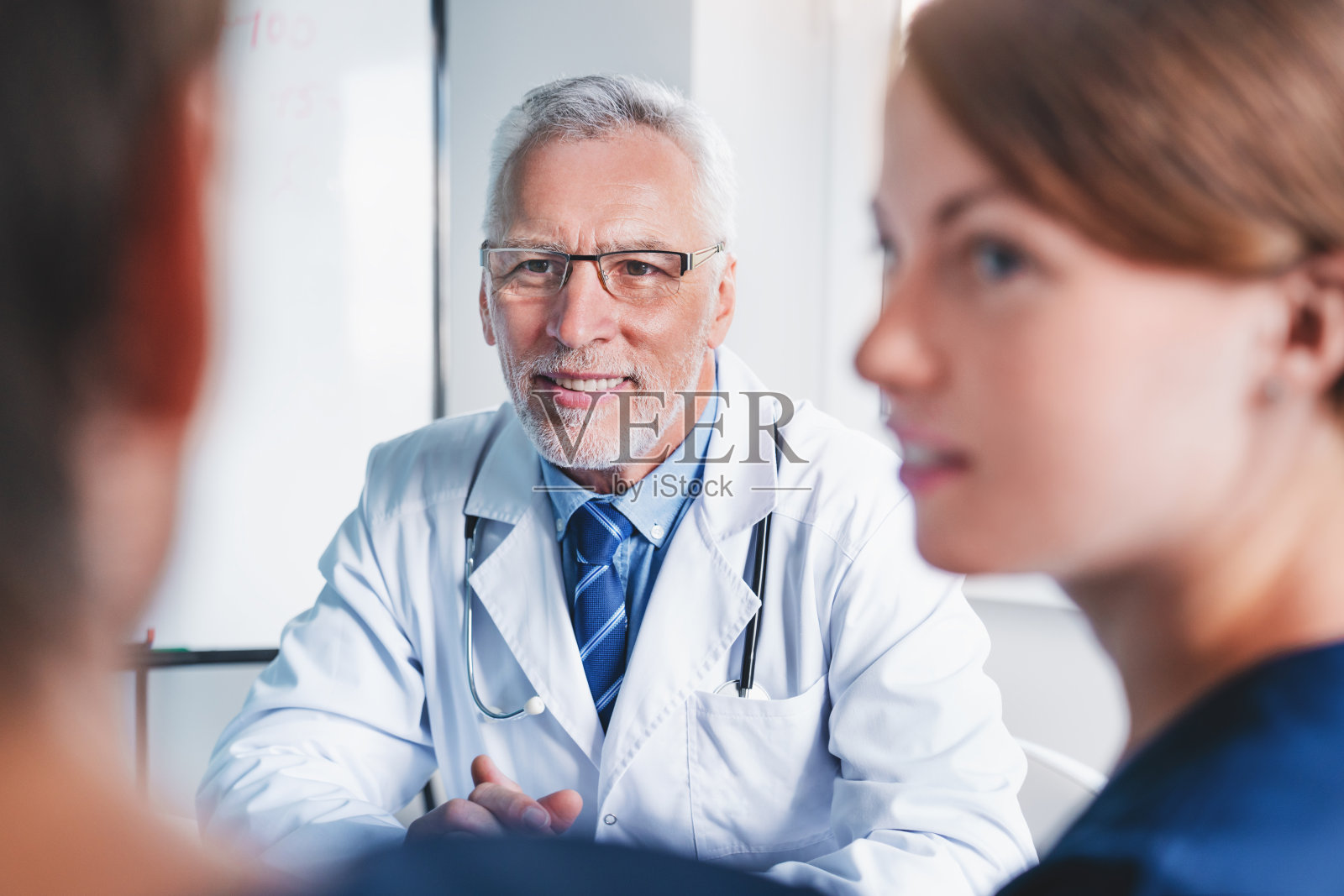 高级医生在会议室与同事开会。照片摄影图片