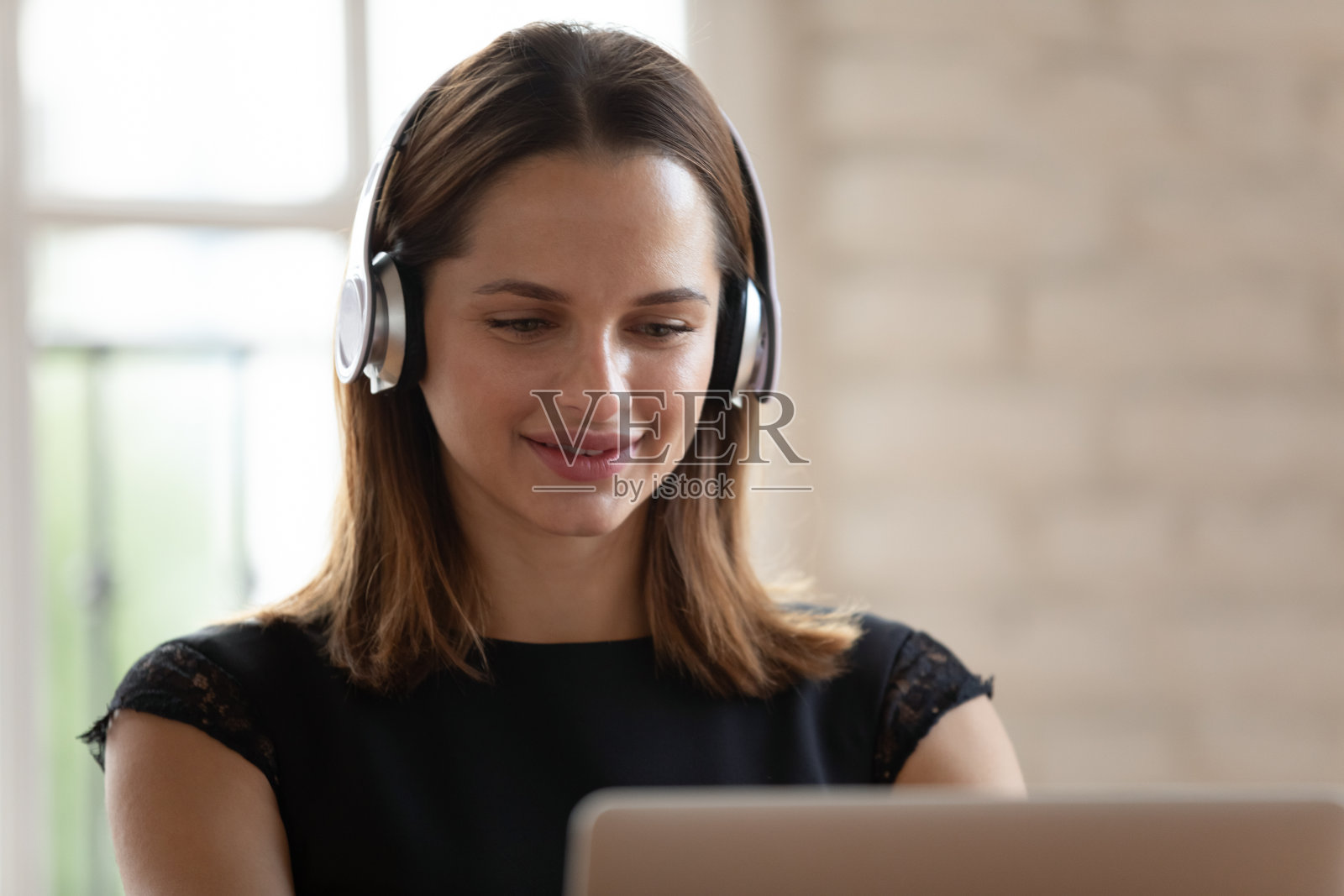 白种女人戴着耳机忙着玩电脑照片摄影图片