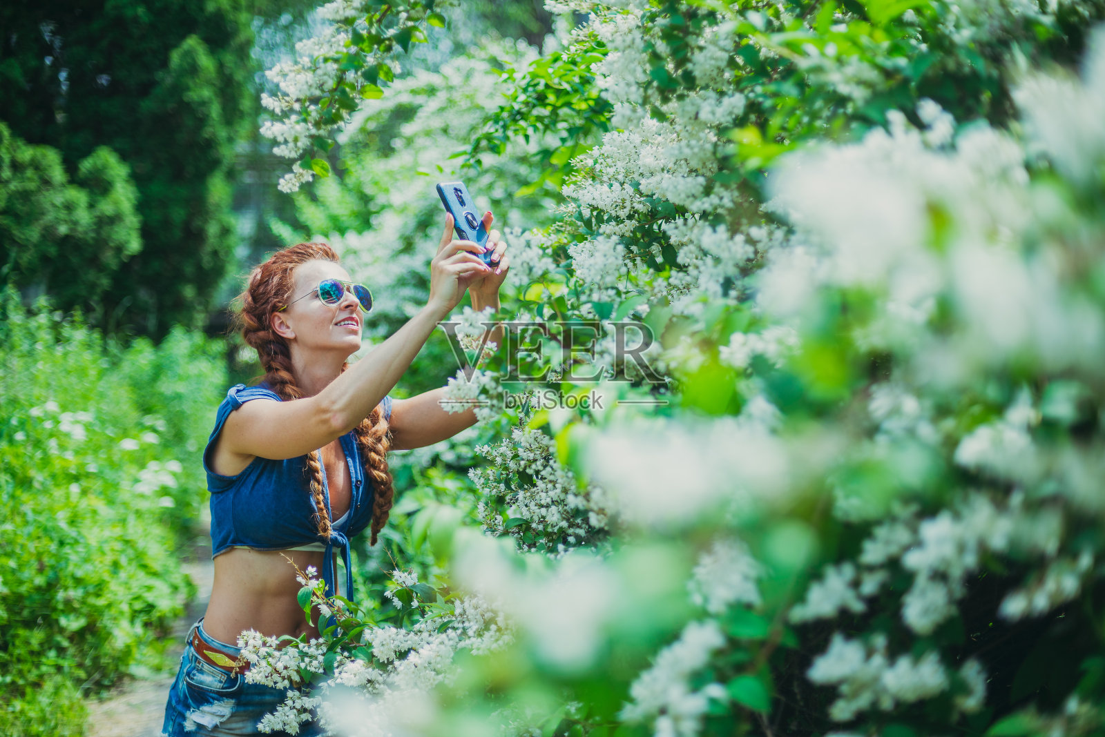 智能手机。一名年轻女子在智能手机上取花。照片摄影图片