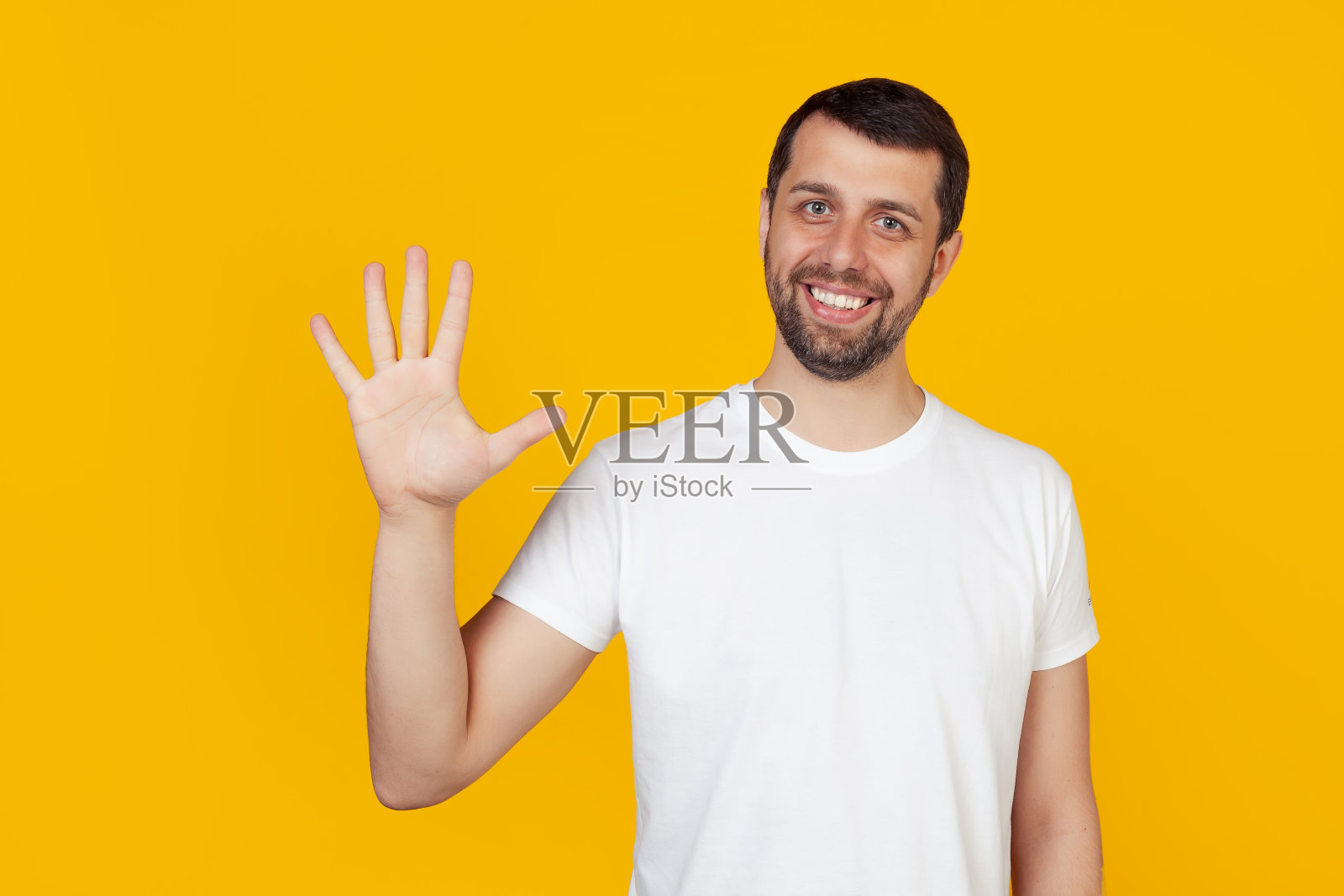 一名留着胡子的年轻男子，穿着白色背心，对着镜头自信而快乐地微笑着，向观众展示了5号。5号。黄色背景照片摄影图片