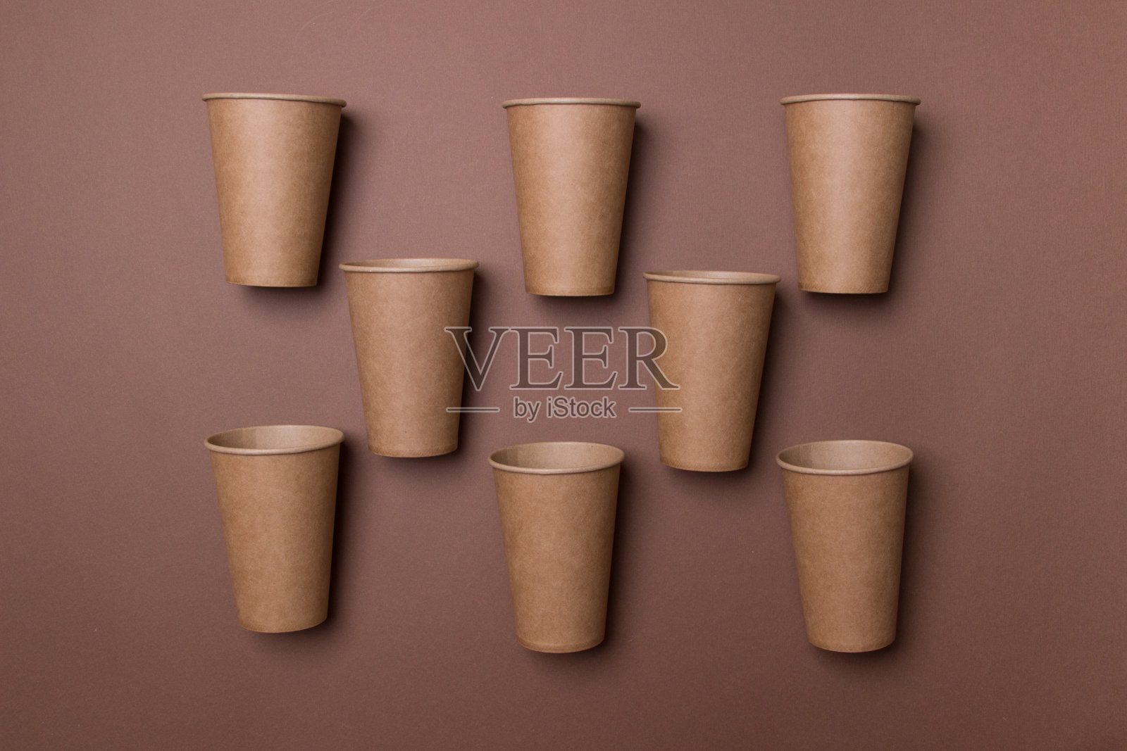 八个棕色环保纸板杯按棋盘顺序躺在棕色纸背景上照片摄影图片