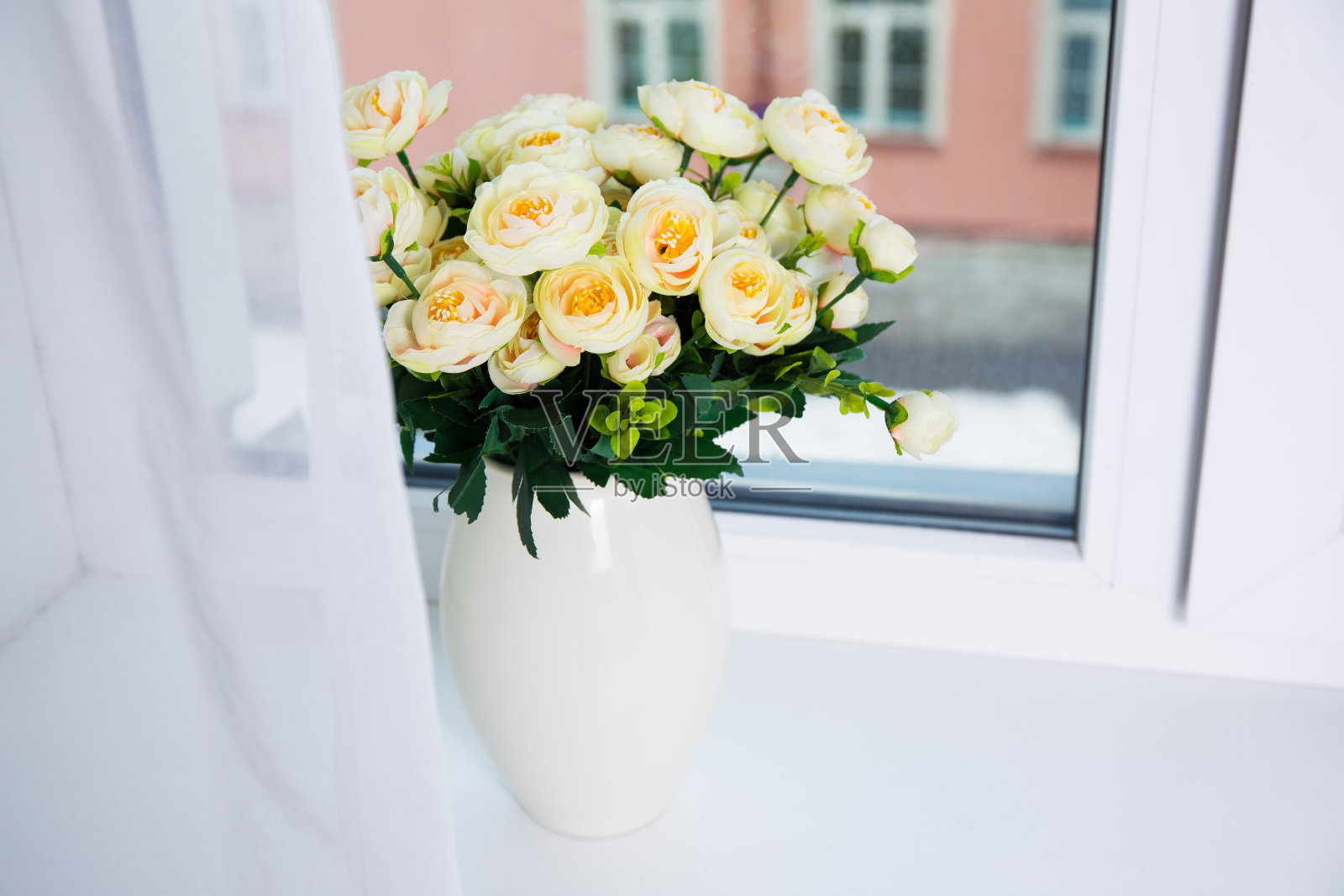 一束美丽的玫瑰花插在窗户上的陶瓷花瓶里照片摄影图片