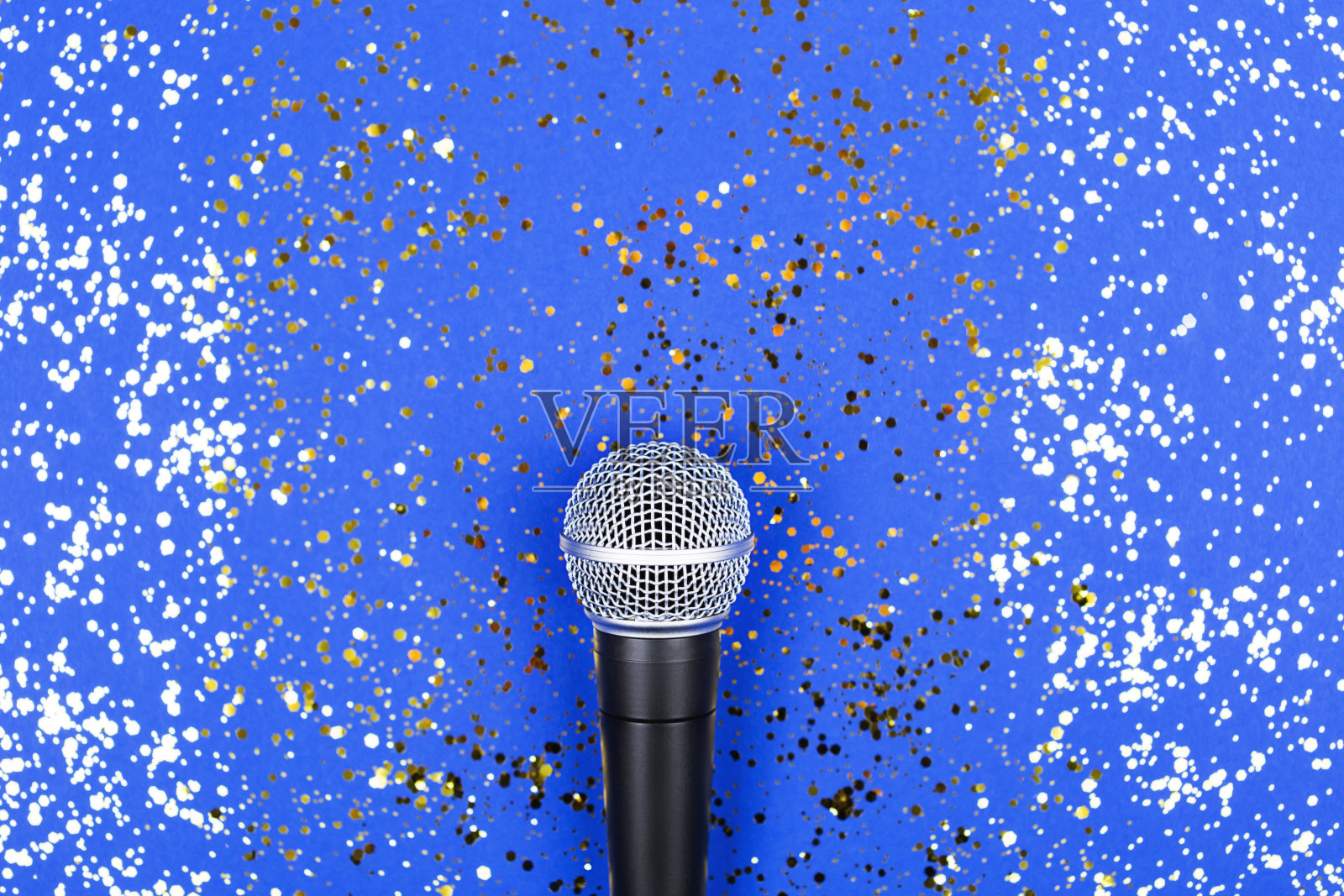 蓝色背景上装饰着五彩纸屑的麦克风。最小的原料油。照片摄影图片