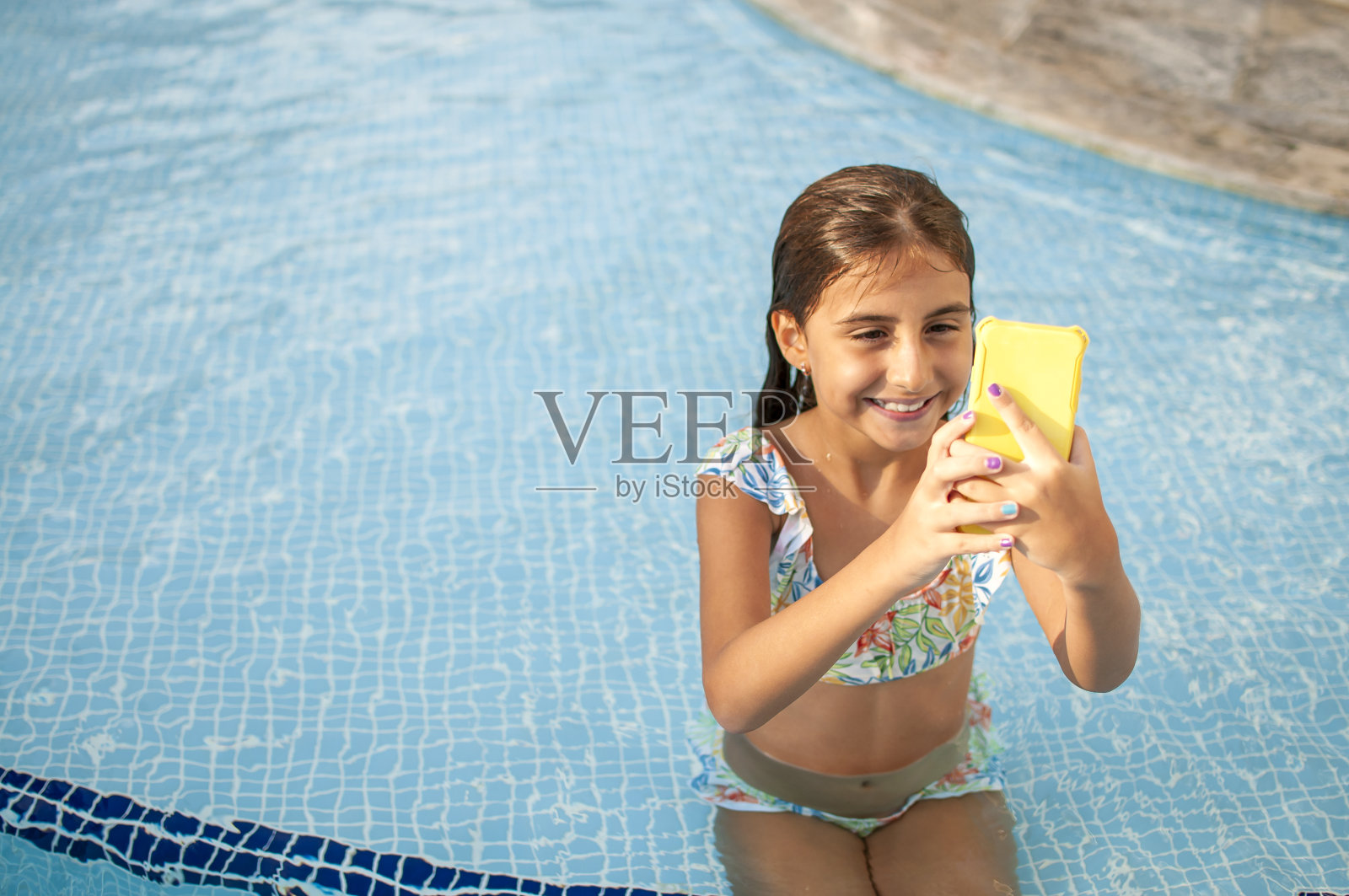 小女孩在游泳池里玩手机照片摄影图片