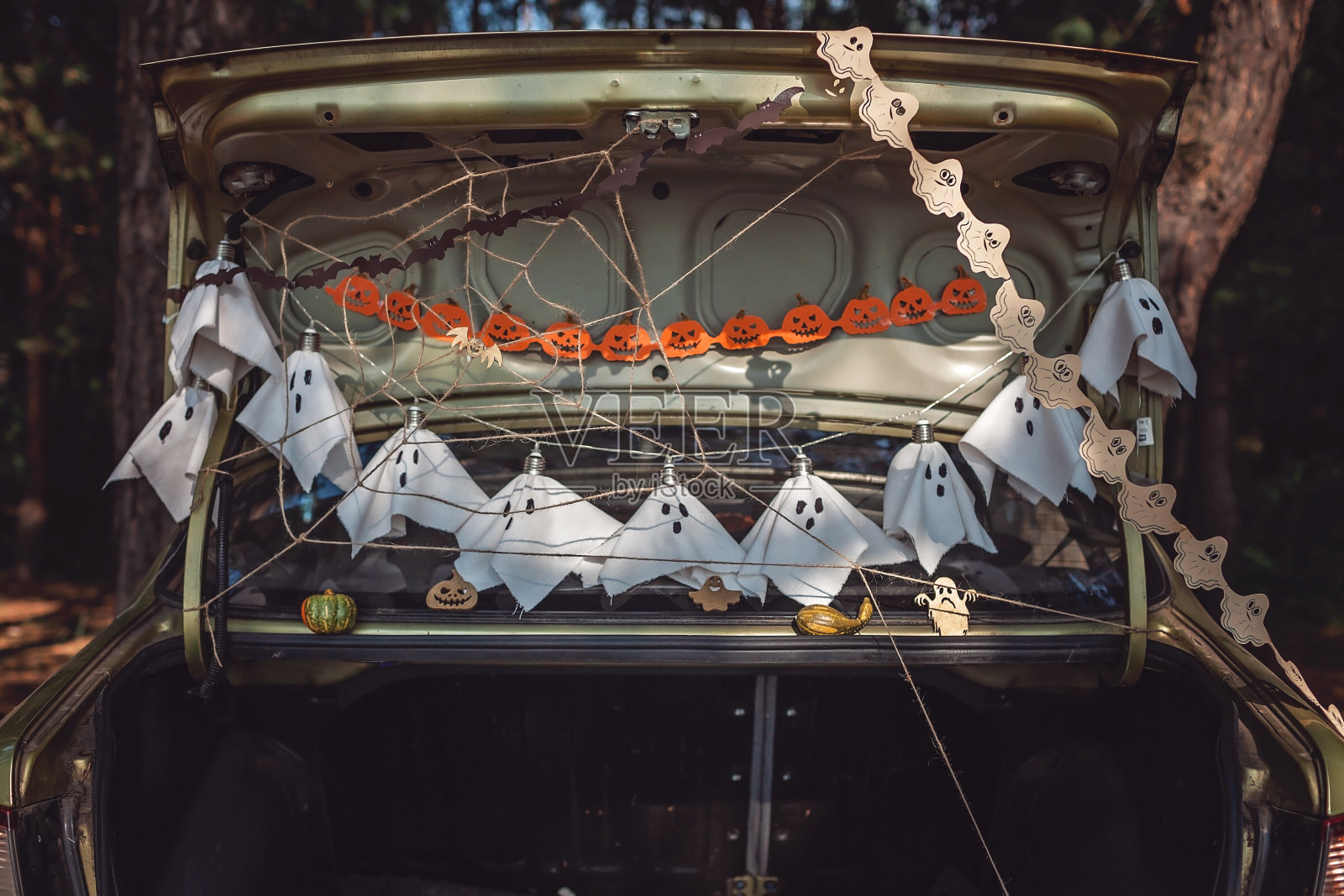 平安遥远庆祝万圣节。孩子们在汽车后备箱里为派对准备装饰照片摄影图片