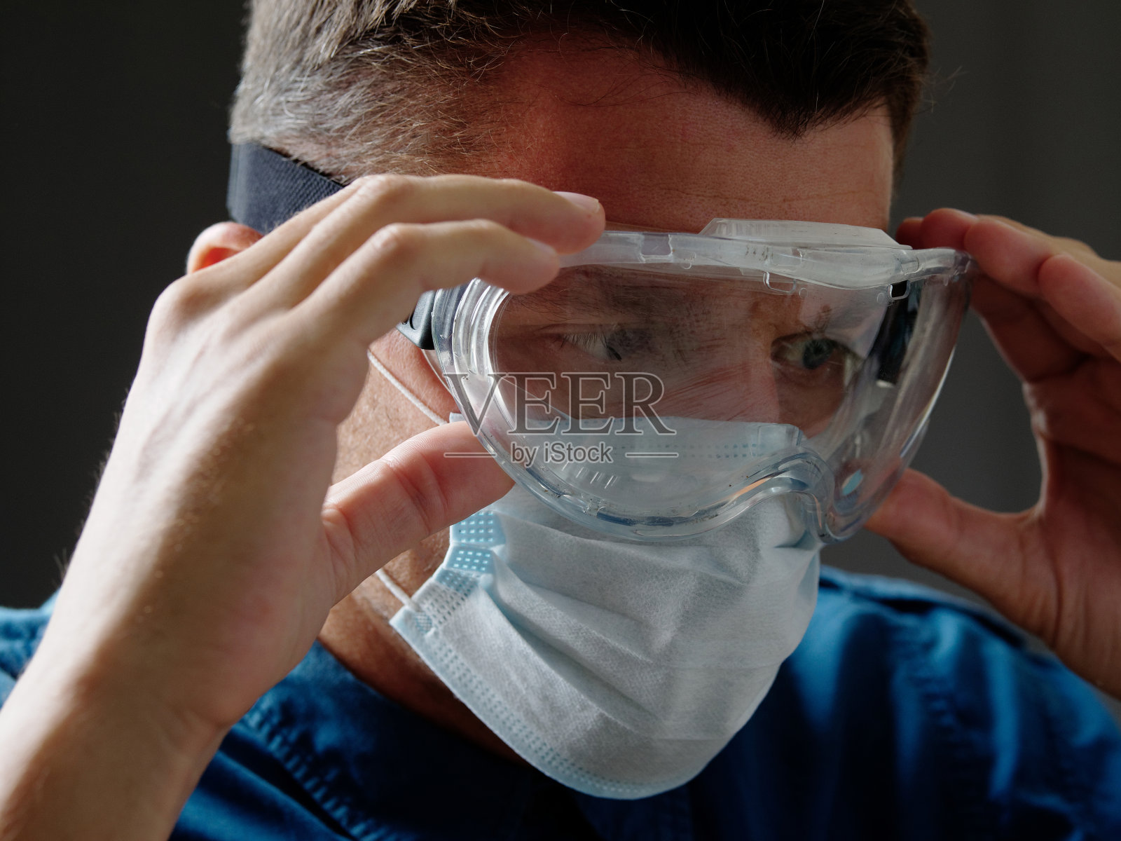 肖像一名男子在医疗口罩戴上护目镜。照片摄影图片
