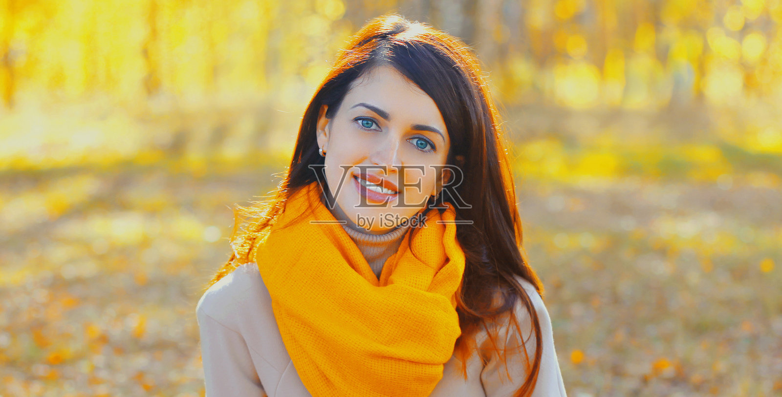 美丽的黑发女人的肖像戴着围巾在秋天的公园照片摄影图片