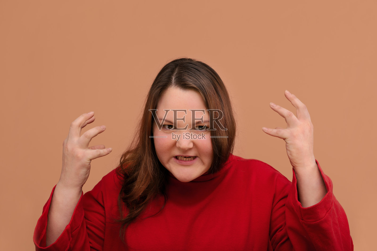 一名愤怒的年轻女子孤立地站在米色背景上。照片摄影图片