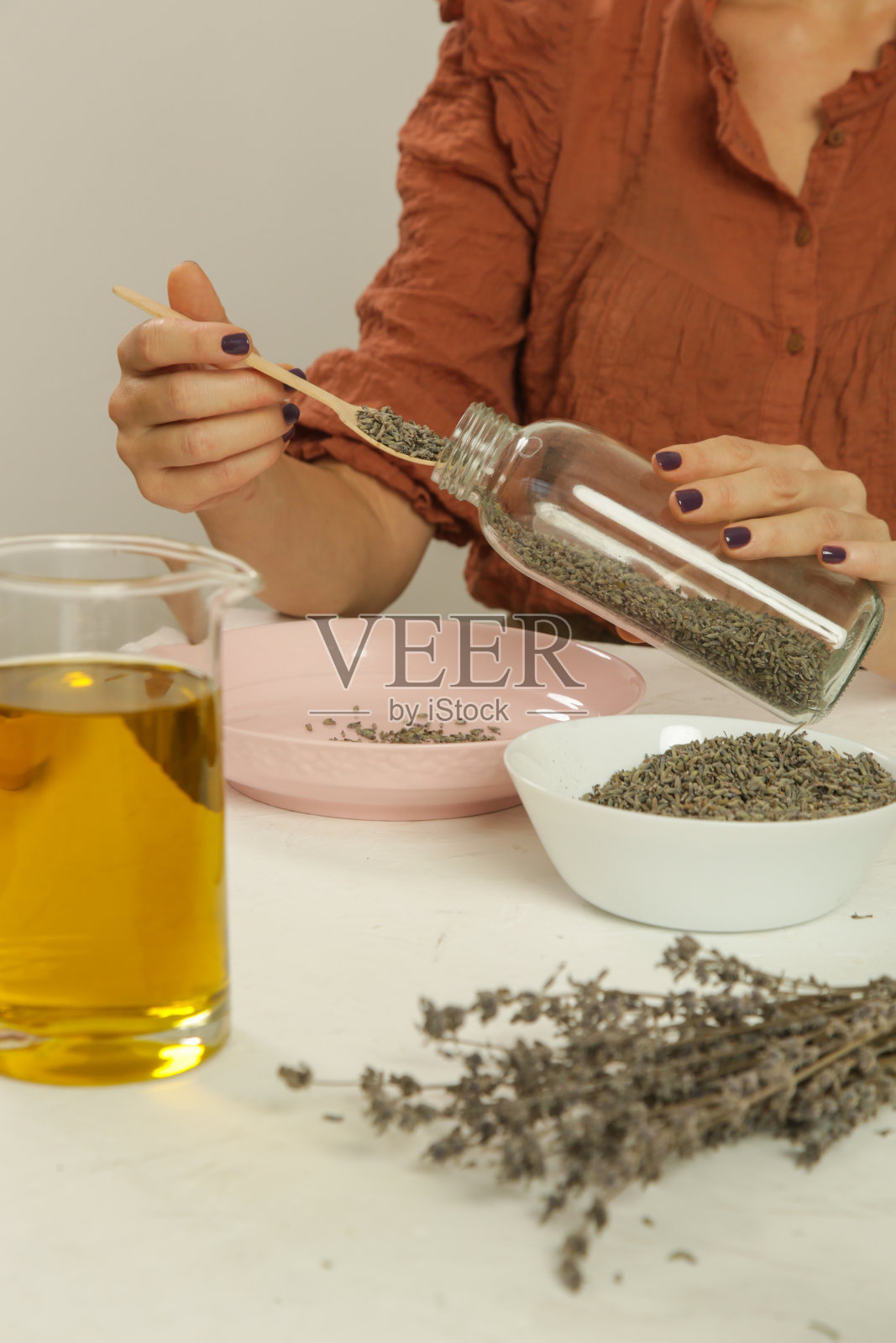 用薰衣草做草药油的女人。天然有机自制化妆品的浸渍工艺。联赛的照片。照片摄影图片