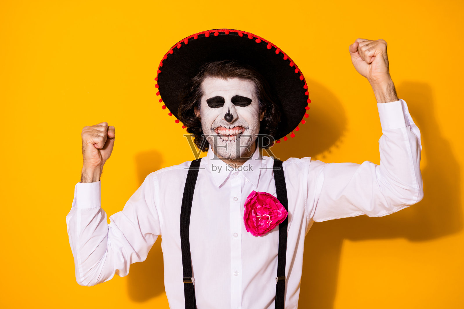 可怕的僵尸家伙举起手拳头愉快的闭上眼睛赢得premium地方文化节穿白衬衫死亡服装糖骷髅吊带孤立的黄色背景照片摄影图片