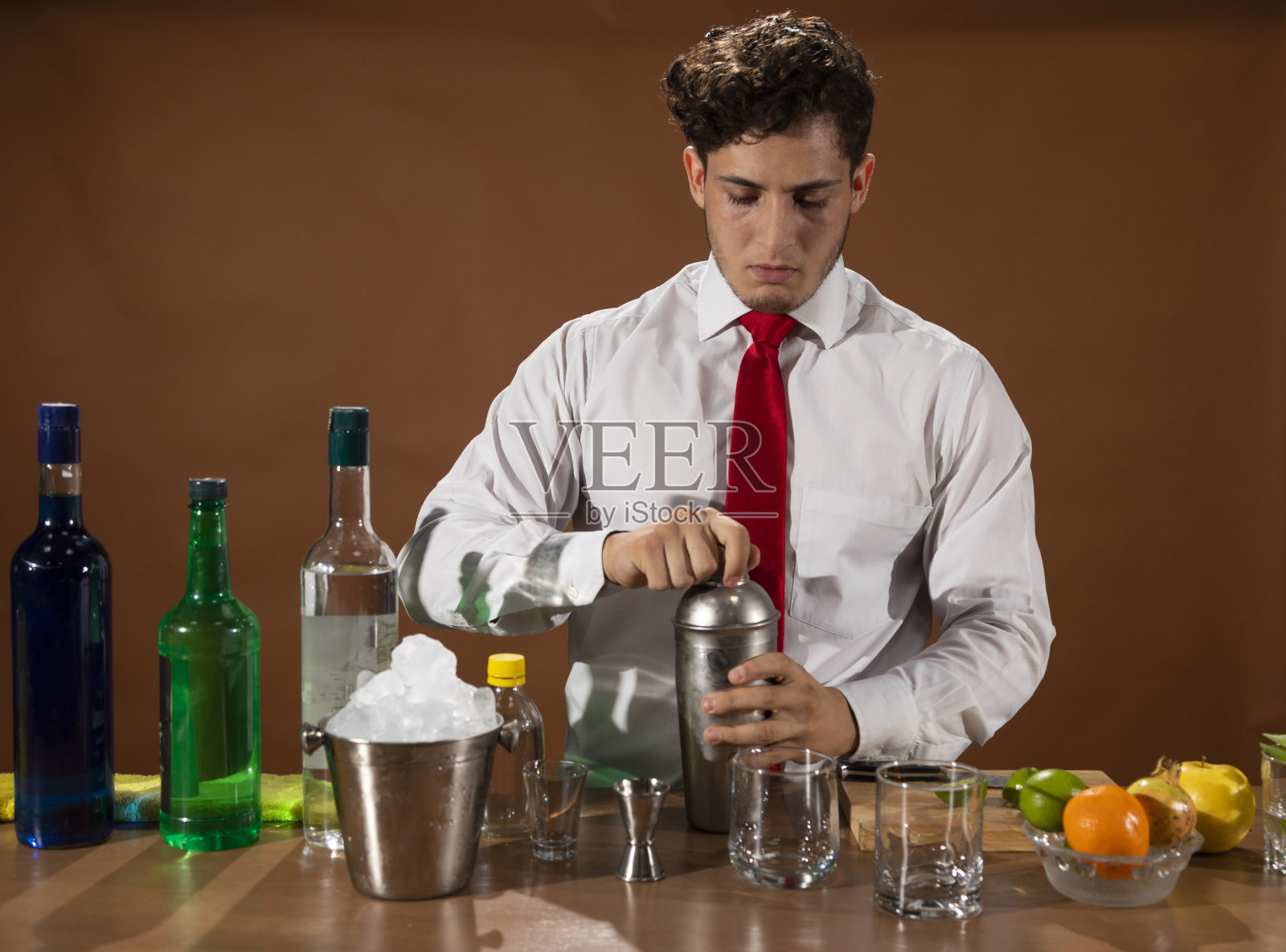 酒保准备酒精饮料与鸡尾酒调酒器在酒吧与一些酒杯利口酒。照片摄影图片