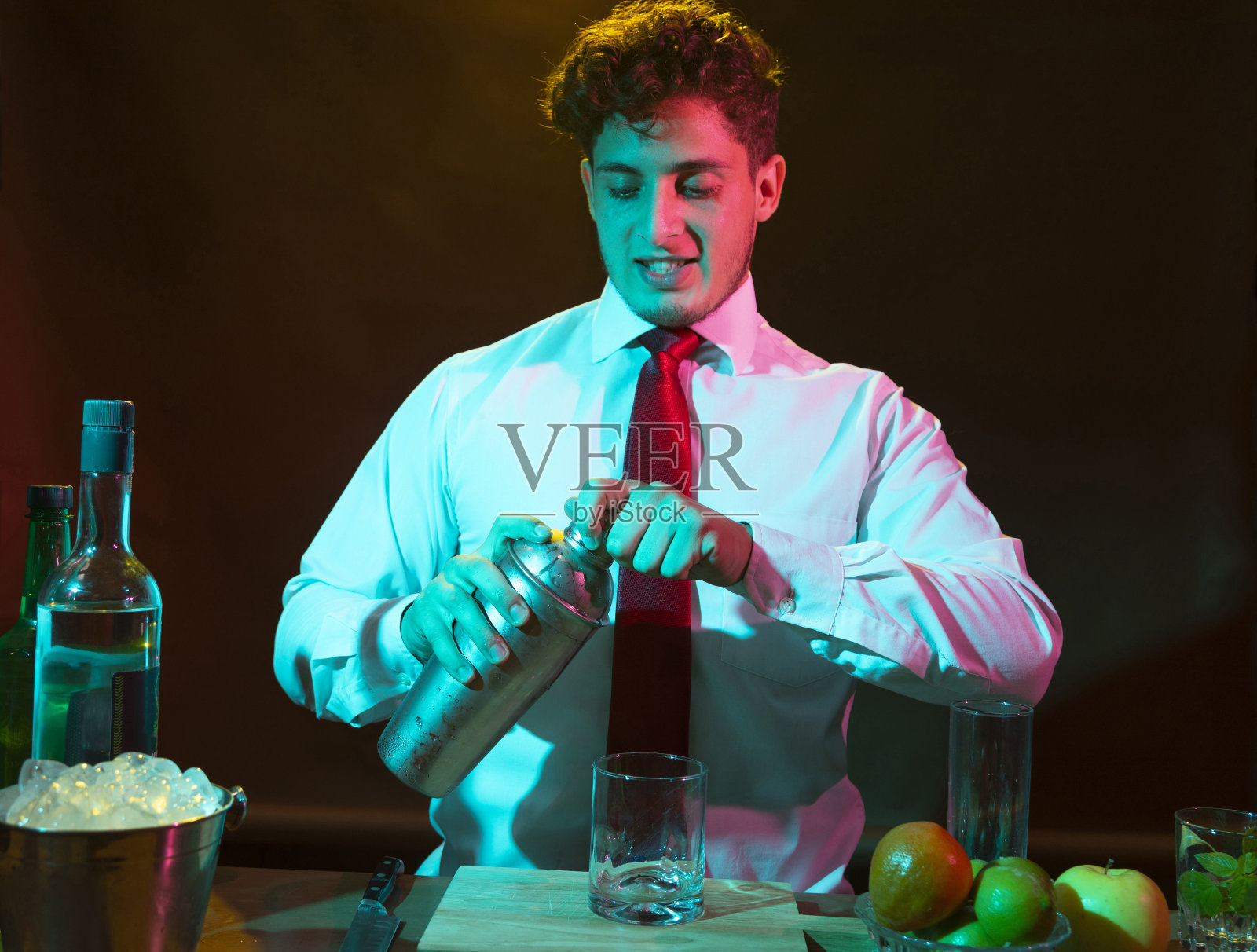 酒保准备酒精饮料与鸡尾酒调酒器在酒吧与一些酒杯利口酒。照片摄影图片