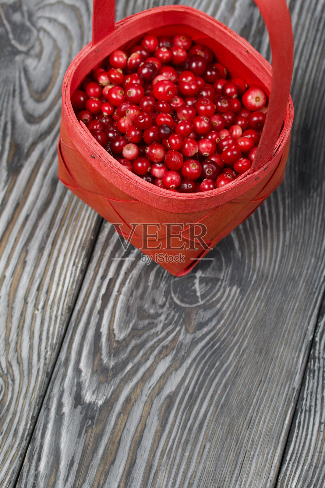 红篮子里的蔓越莓。在黑色的黑板上，具有富有表现力的木质纹理。照片摄影图片