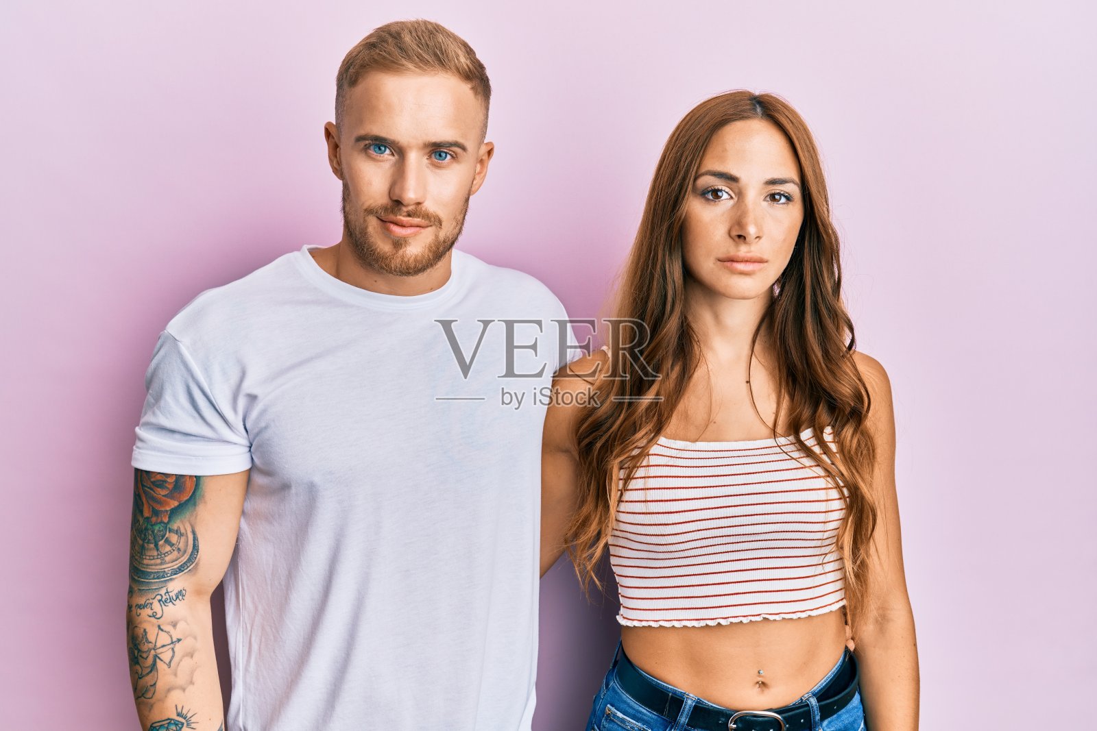 年轻的一对女友和男友拥抱在一起，神情轻松，脸上带着严肃的表情。简单自然的看相机。照片摄影图片