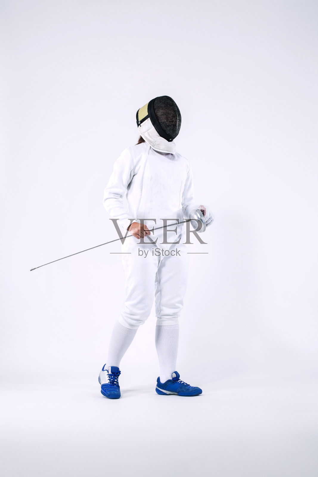 击剑运动员戴着面具和白色击剑服，手持剑。在白色背景上隔离照片摄影图片