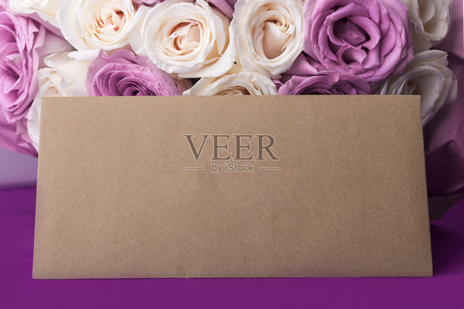 新鲜的白色和紫色玫瑰和工艺信封。给节日母亲，情人节，生日，周年纪念日和婚礼的礼物。礼物包装的概念。为文本复制空间。照片摄影图片