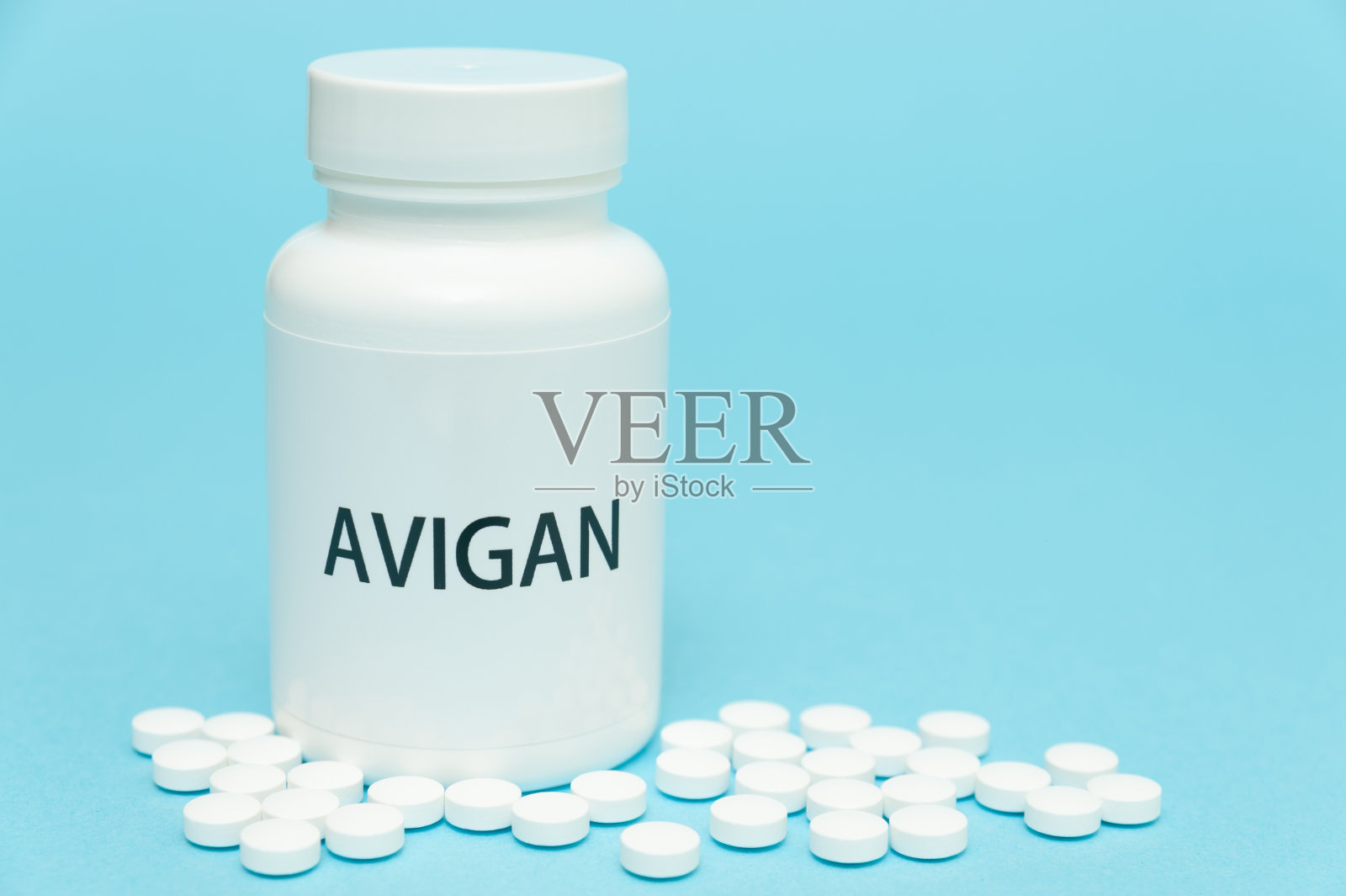 AVIGAN(法维拉韦)白瓶包装，内含散粒药丸。治疗COVID-19。孤立在蓝色背景。副本的空间。特写镜头。水平射照片摄影图片