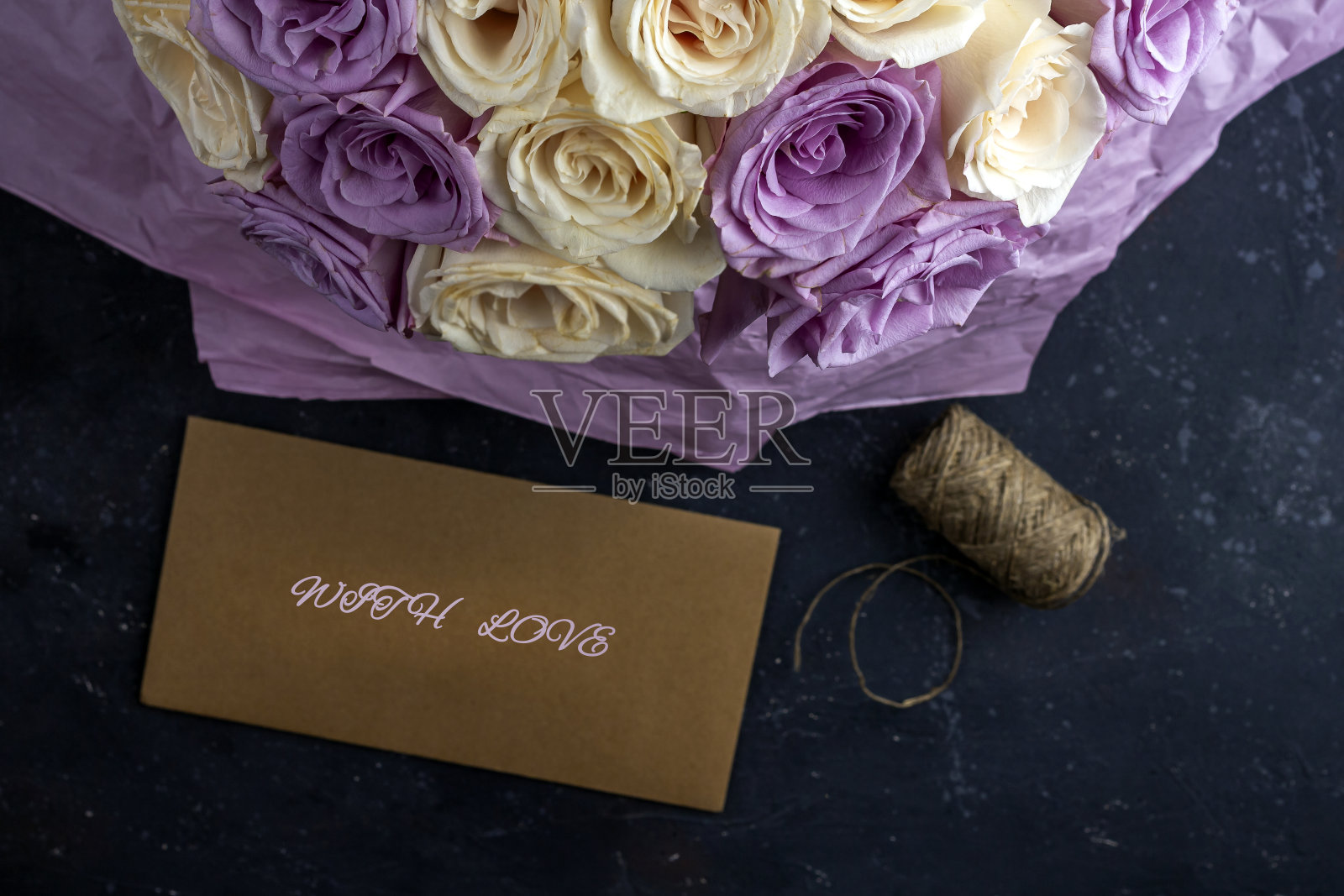 新鲜的白色和紫色玫瑰和工艺信封。给节日母亲，情人节，生日，周年纪念日和婚礼的礼物。礼物包装的概念。为文本复制空间。照片摄影图片