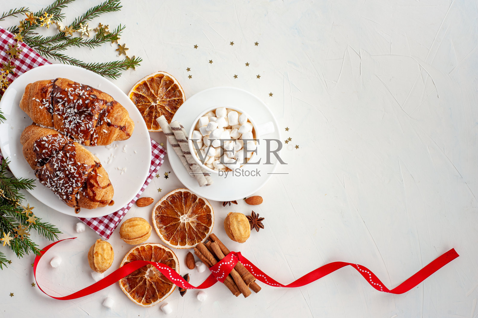 圣诞早餐。圣诞节的早晨。一杯可可，棉花糖和羊角面包，在一个装饰过的圣诞树的树枝的浅混凝土背景。文本。从以上观点。照片摄影图片