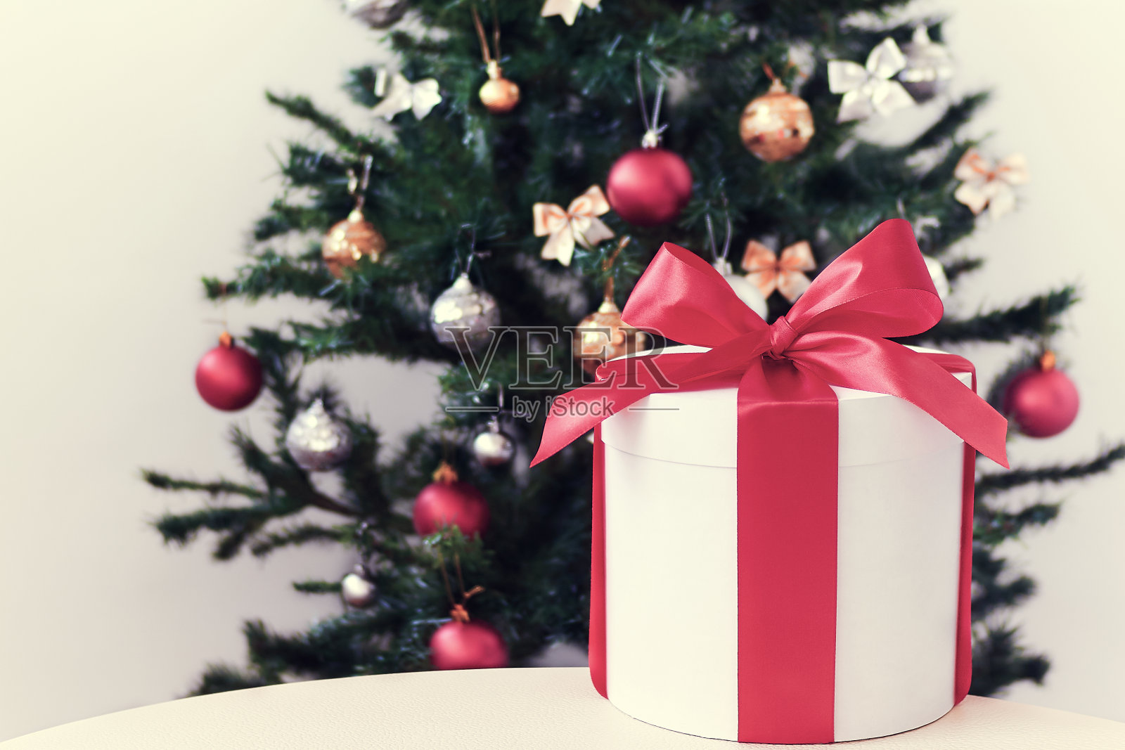 圣诞白色礼盒与洋红色丝带在桌子上装饰圣诞树的背景。照片摄影图片