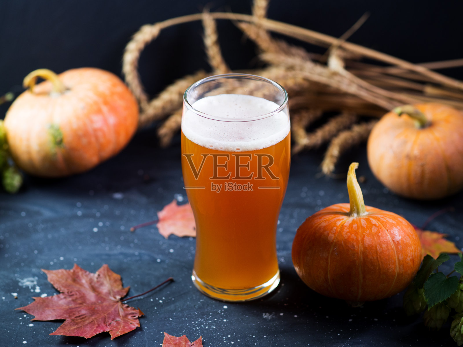 啤酒节的季节性啤酒装饰在一张深色的桌子上。手工制作的啤酒照片摄影图片