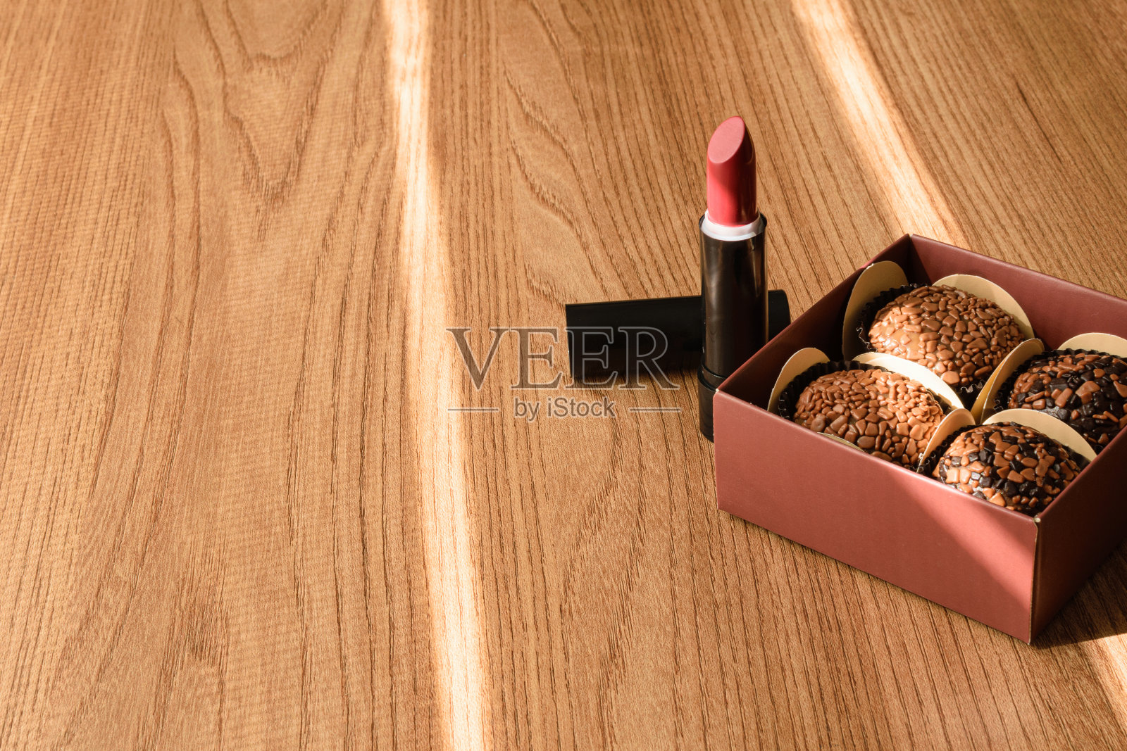 盒子里有4个准将和1支口红，被阳光照亮。照片摄影图片