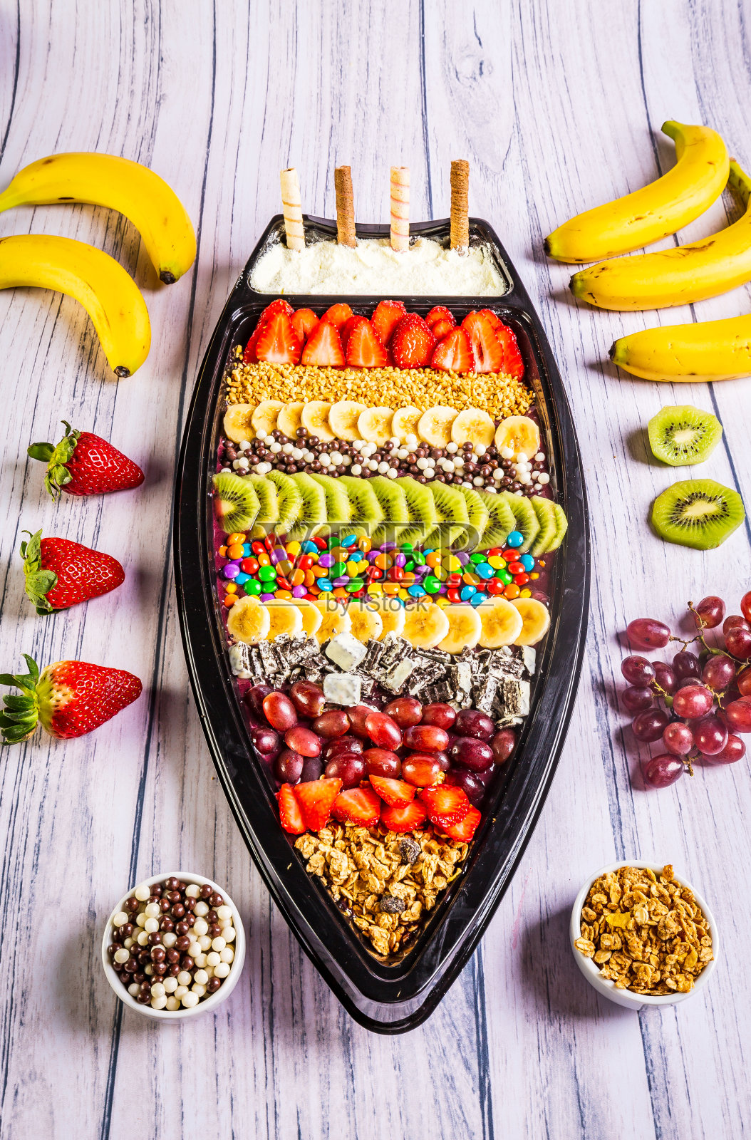冷冻巴西莓配香蕉、猕猴桃、格兰诺拉麦片和糖果。一艘供大家分享的船。照片摄影图片