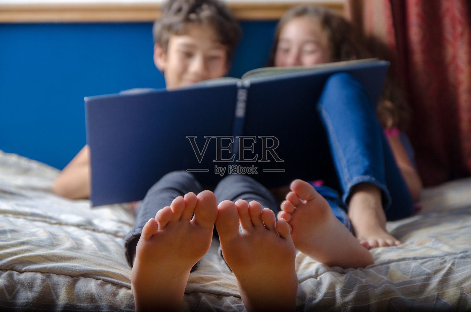 在床上一起读书的年轻女孩和男孩照片摄影图片