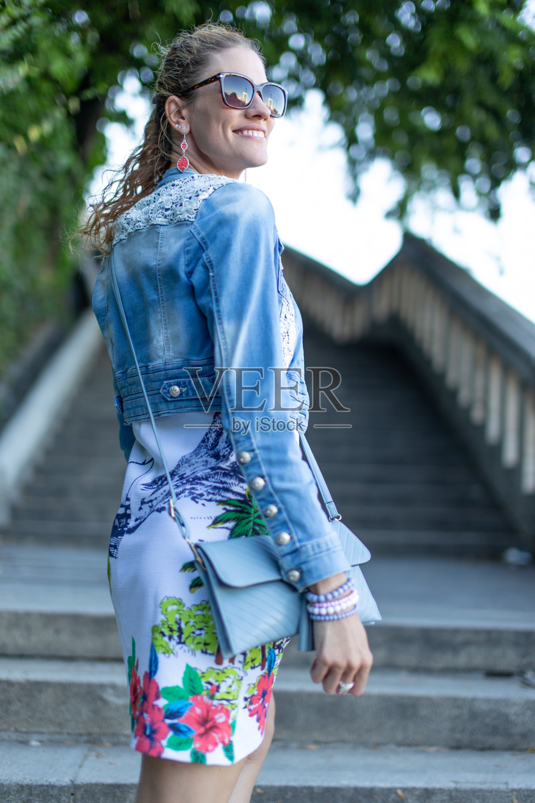 年轻的白人城市女人戴着墨镜在公园里看别处照片摄影图片